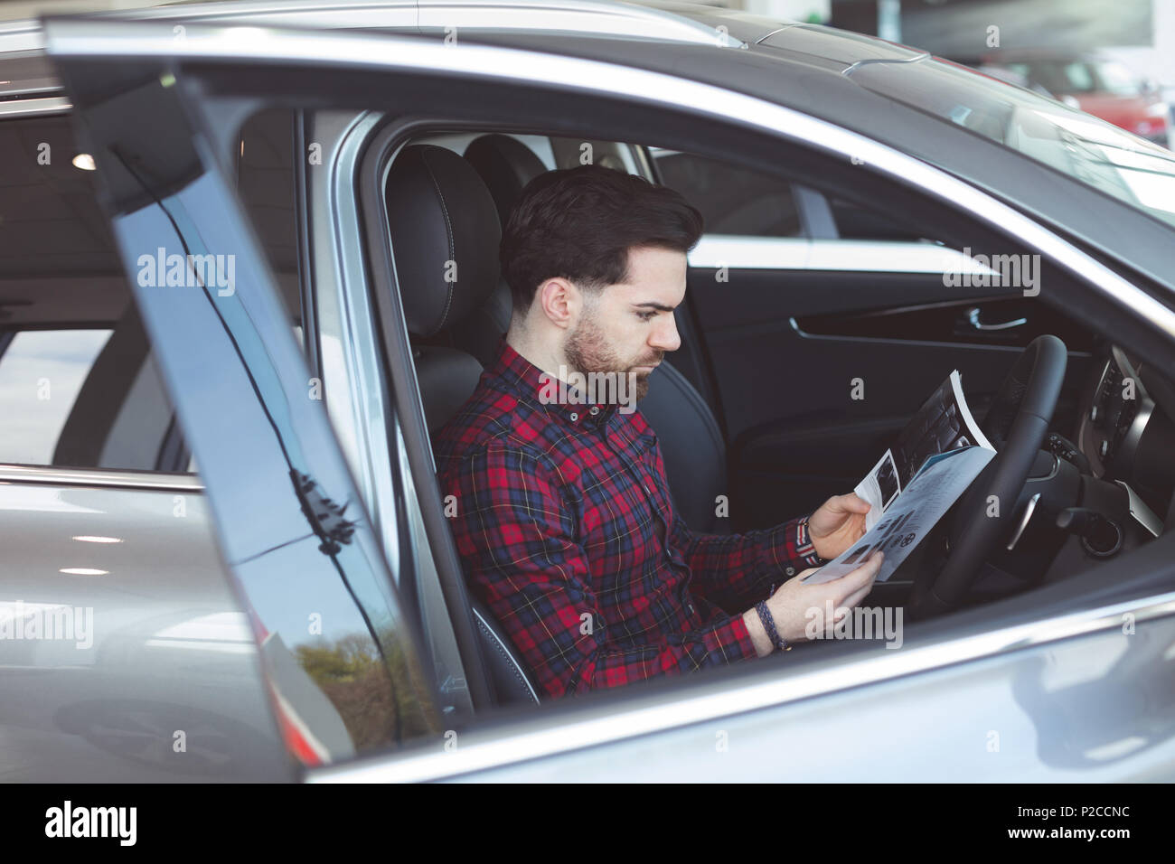 Salesman reading brochure inside the car Stock Photo