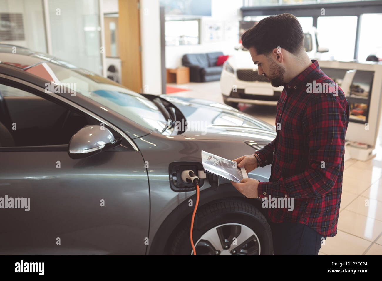 Salesman standing next to car and reading brochure Stock Photo