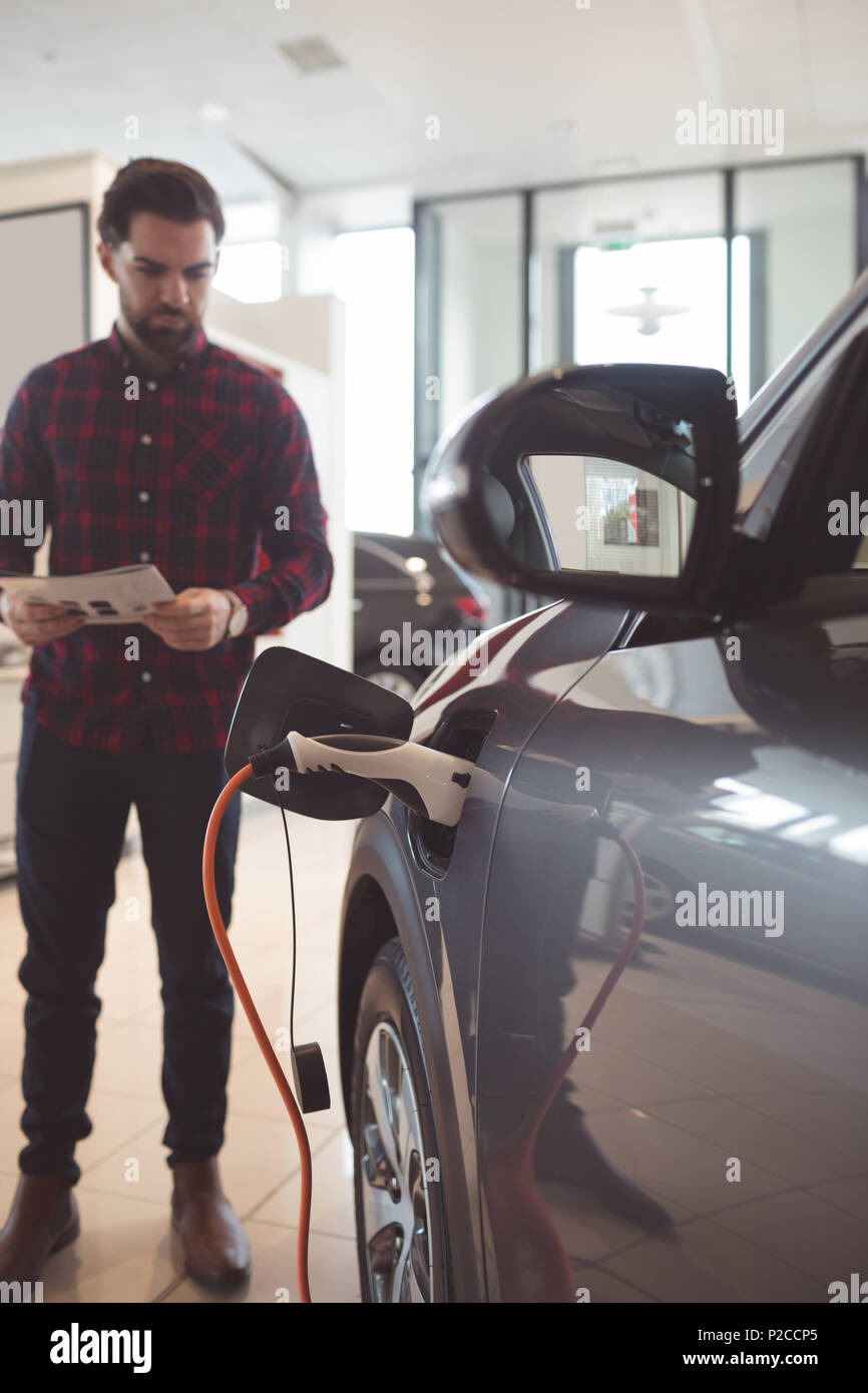 Salesman standing next to car and reading brochure Stock Photo