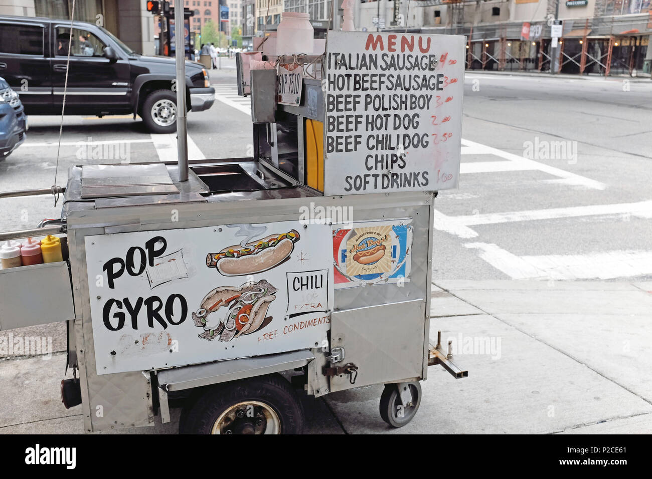 Hot dog cart with menu of avaiable items with prices rests on a sidewalk in downtown Cleveland, Ohio, USA. Stock Photo