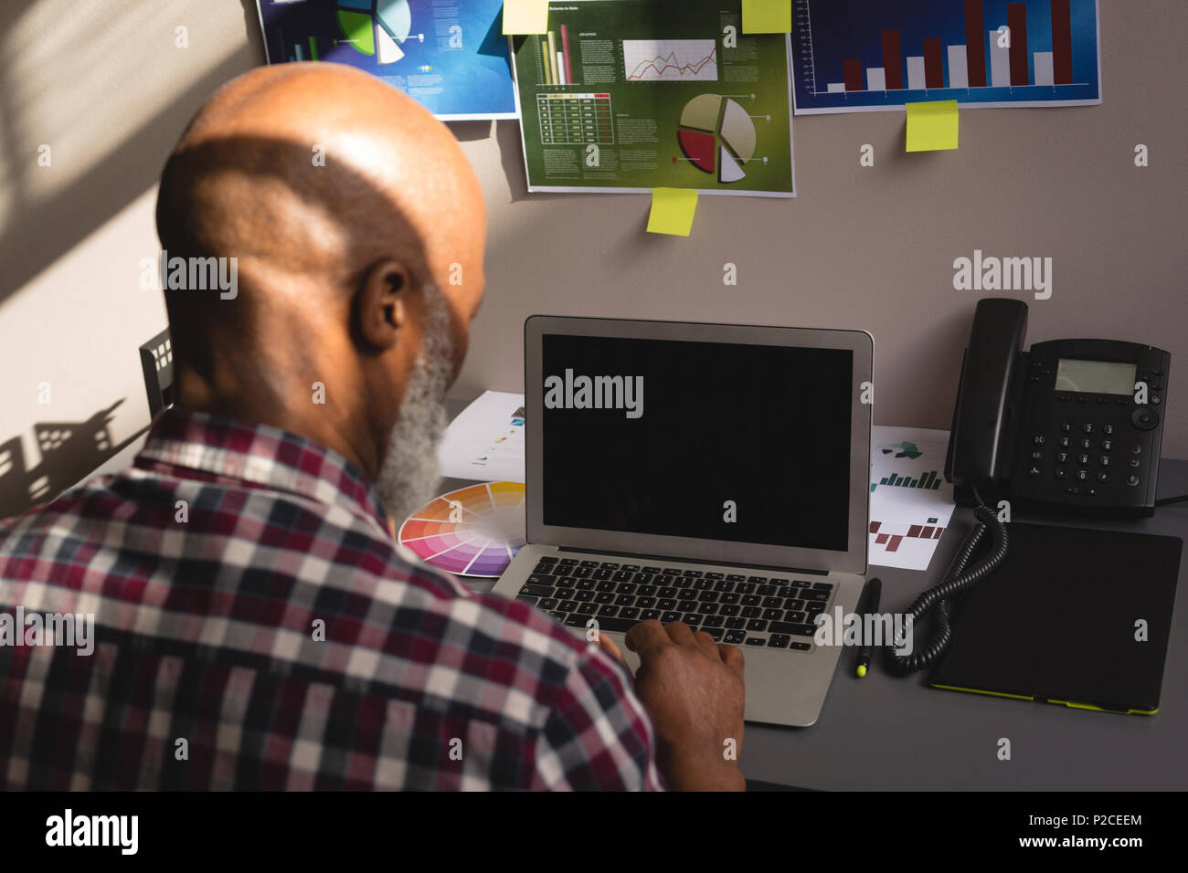 Senior graphic designer using laptop at desk Stock Photo