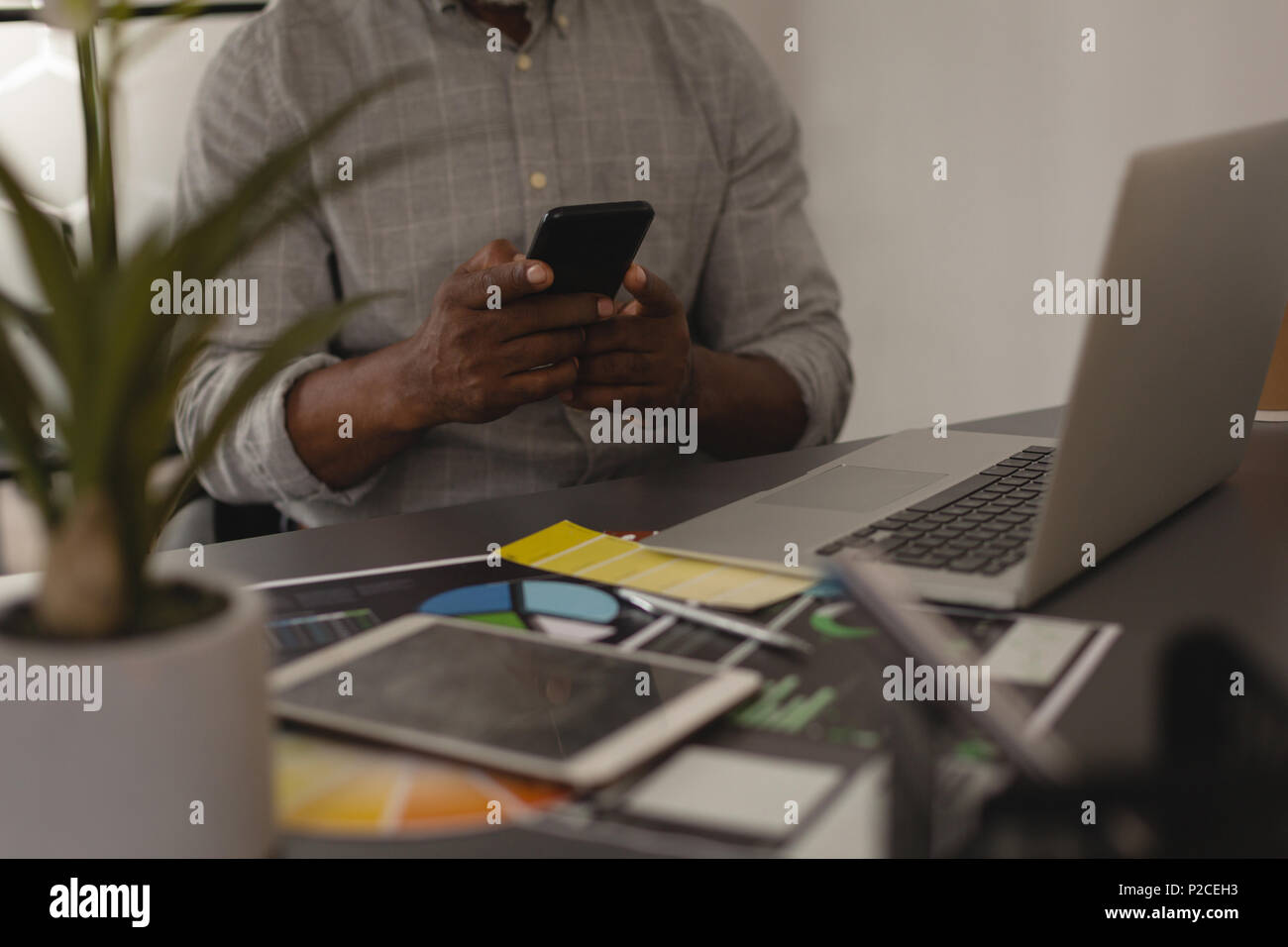 Senior graphic designer using mobile phone in office Stock Photo