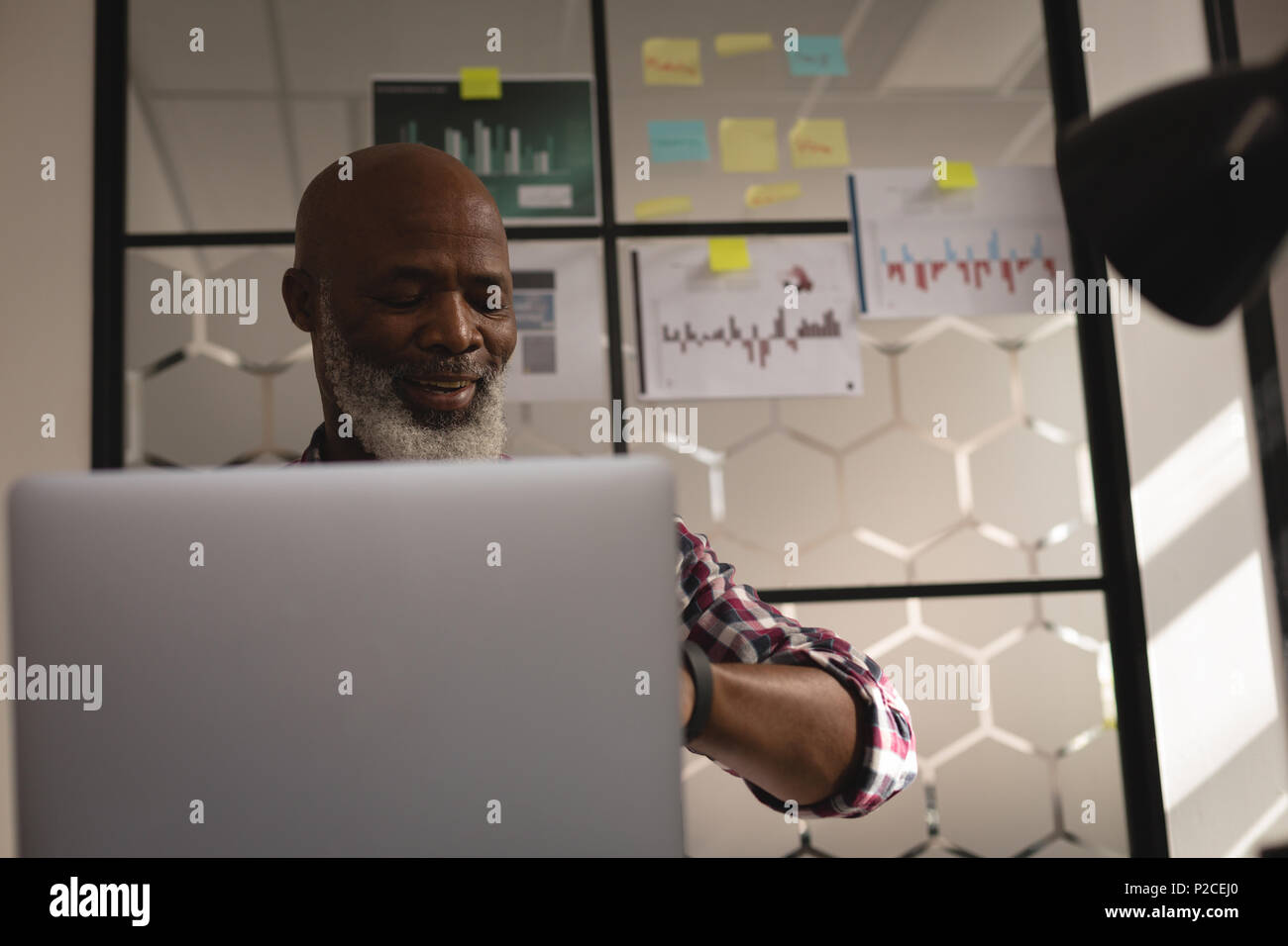 Senior graphic designer using laptop at desk Stock Photo