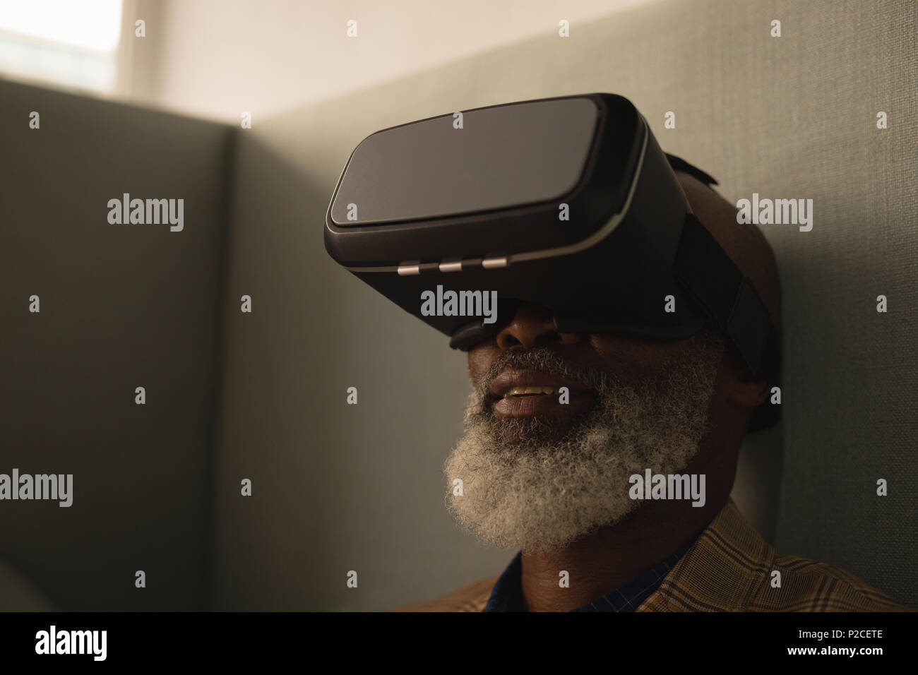 Senior graphic designer using virtual reality headset in cafeteria Stock Photo