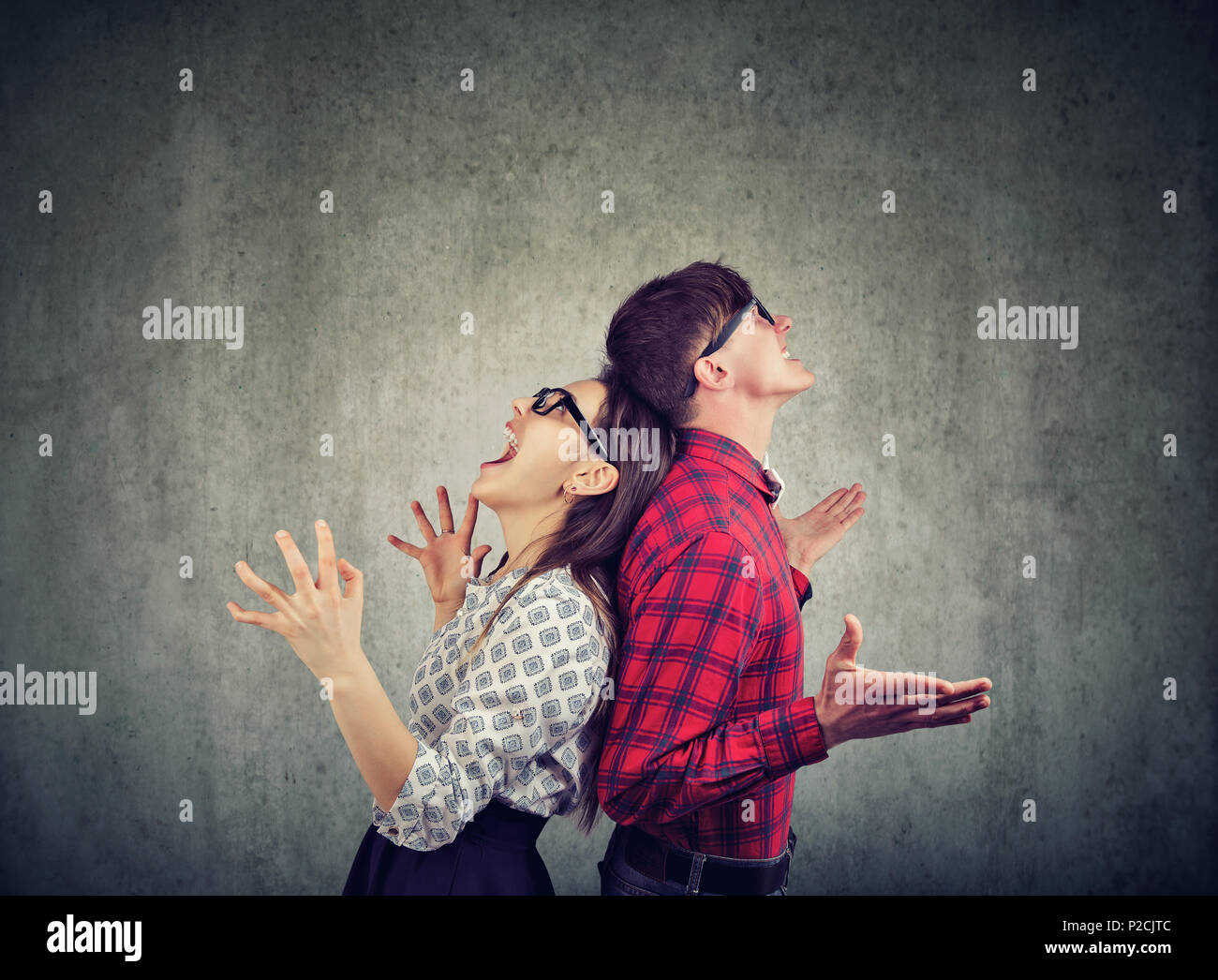 Side view of man and woman in glasses standing back to back screaming in frustration Stock Photo