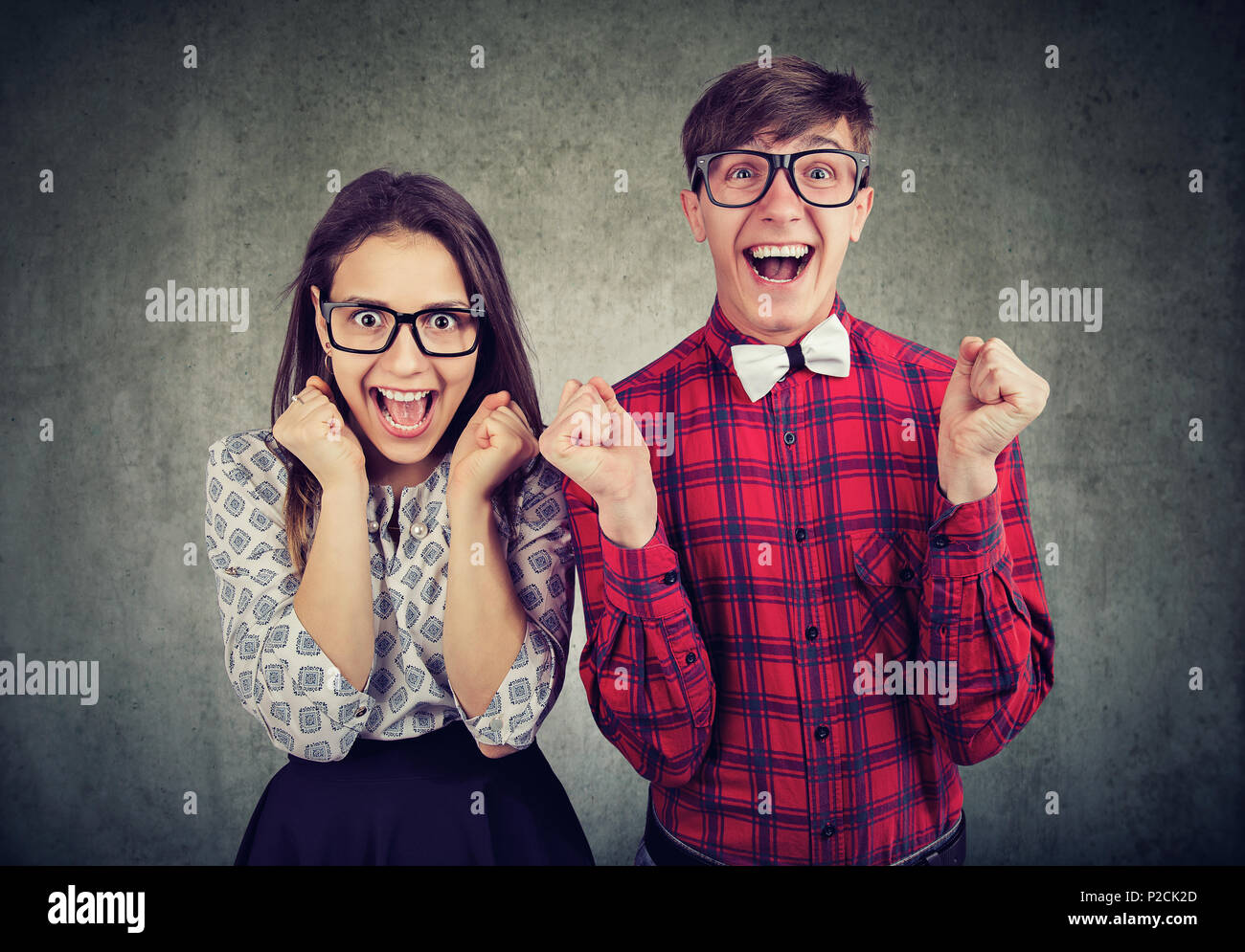 Casual young man and woman with funny expression screaming with excitement looking at camera. Stock Photo