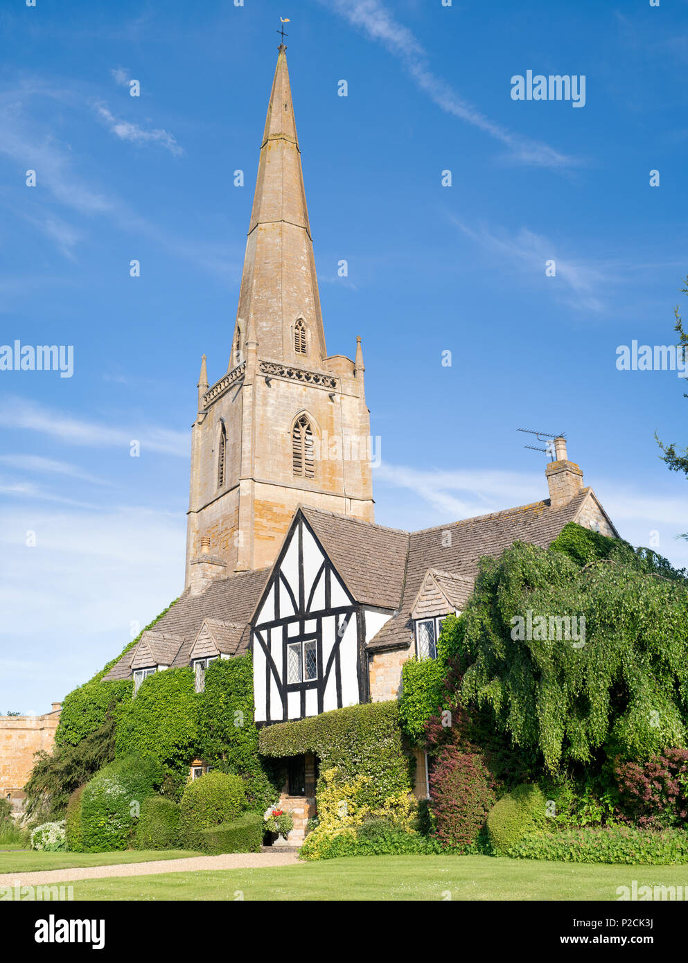Large house covered by foliage in front of St Gregorys church in the village of Tredington, Warwickshire, England Stock Photo