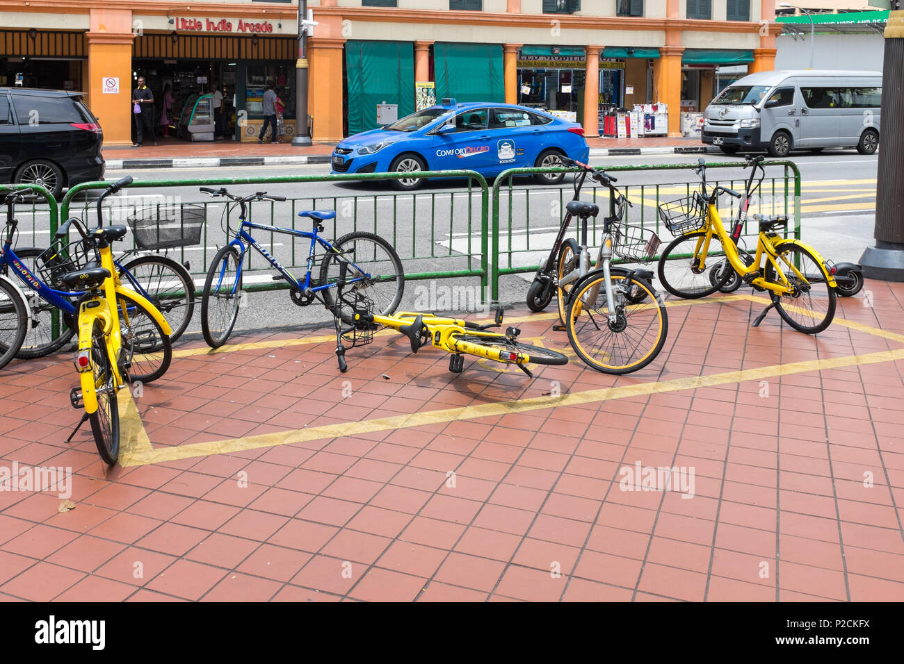 Yellow public rental bikes left in a designated area on the pavement on Serangoon Road in the Little India district of Singapore Stock Photo