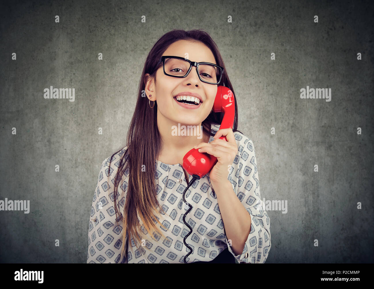Happy attractive young woman talking on retro telephone over wall background Stock Photo