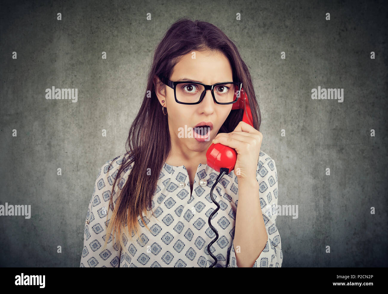 Amazed shocked young woman talking on a telephone Stock Photo