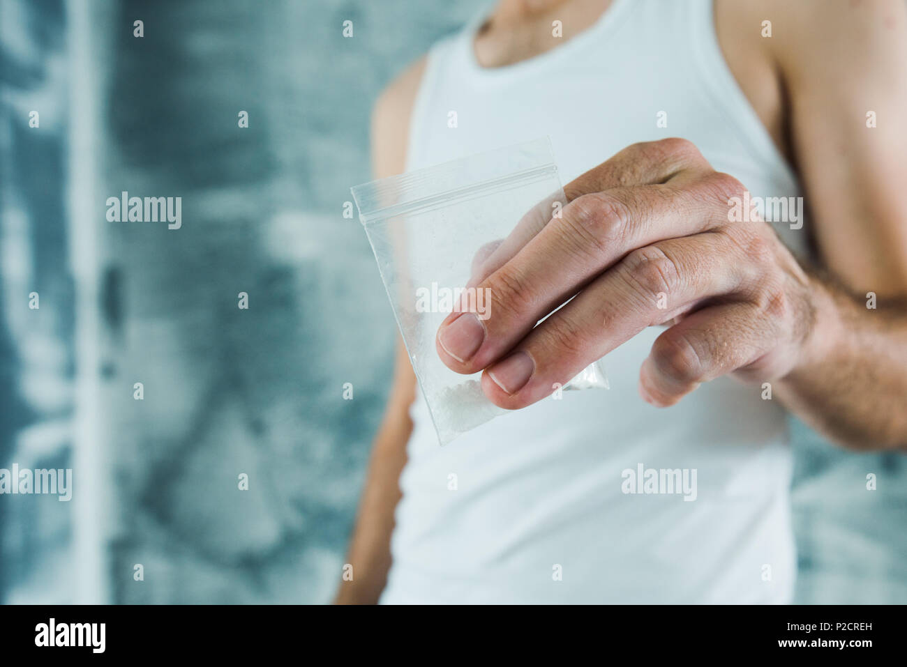 Gang member and drug dealer offering crack cocaine in small plastic bag, close up of hands with selective focus Stock Photo