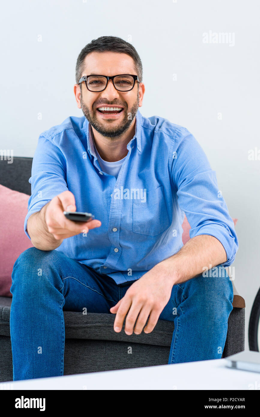 portrait of cheerful man changing channels while watching tv at home Stock Photo