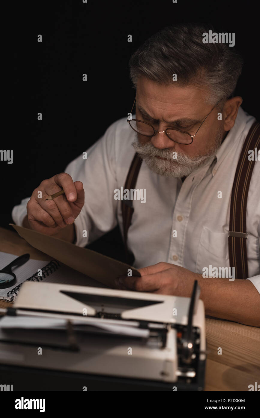 serious senior writer working with manuscript isolated on black Stock ...
