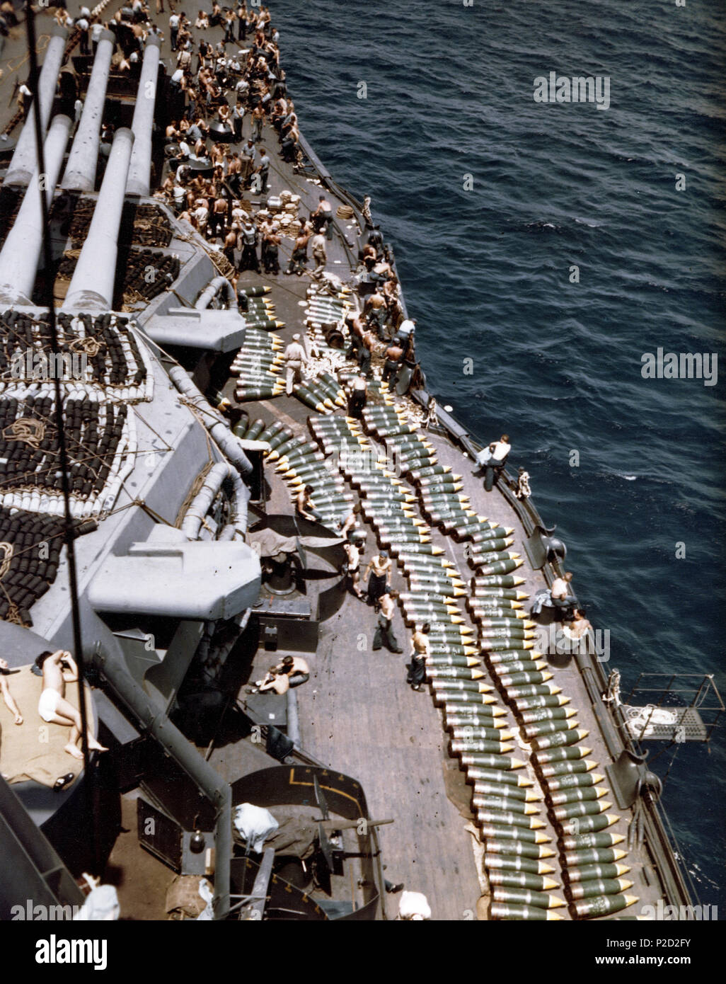 . 14-inch (35.6 cm) projectiles on deck of the U.S. Navy battleship USS New Mexico (BB-40), while the battleship was replenishing her ammunition supply prior to the invasion of Guam, July 1944. The photograph looks forward on the starboard side, with triple 14'/50 gun turrets at left. Note floater nets stowed atop the turrets. July 1944. USN 1 14in shells on deck of USS New Mexico (BB-40) in 1944 Stock Photo