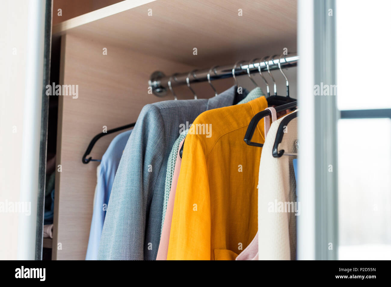 Colorful Female Clothes Hanging On Rack In Cabinet Stock Photo