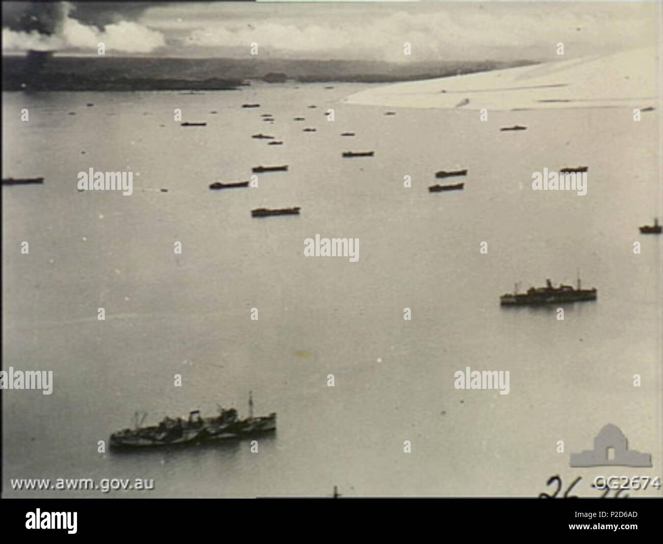 . English: AWM Caption: TARAKAN ISLAND, BORNEO. 1945-05-01. VIEW FROM A RAAF LIBERATOR BOMBER AIRCRAFT OF ALLIED INVASION CRAFT OFF LINGKAS - TARAKAN ISLAND. SMOKE FROM BURNING OIL INSTALLATIONS CAN BE SEEN IN THE DISTANCE. 1 May 1945. Harrison, John Thomas 61 Tarakan shipping (AWM OG2674) Stock Photo