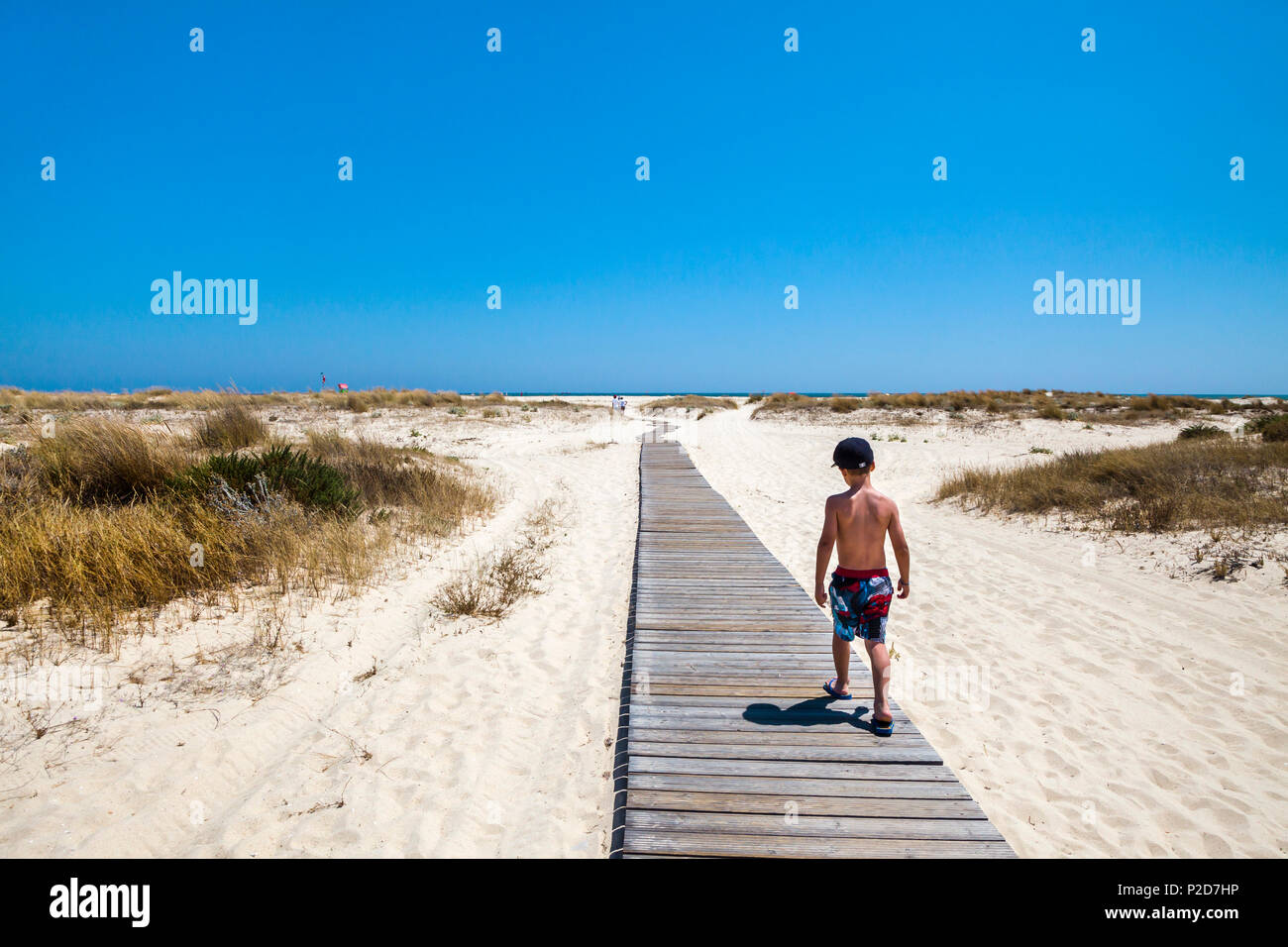 Boy on a boardwalk, walking to the beach, Armona island, Olhao, Algarve, Portugal Stock Photo