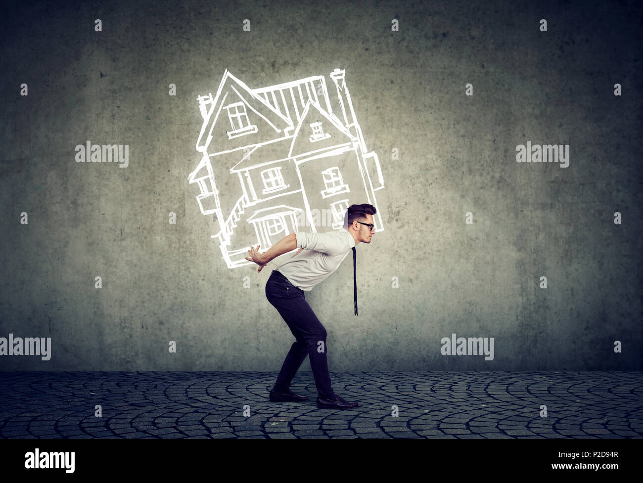 Overburdened business man carrying a house on his back Stock Photo