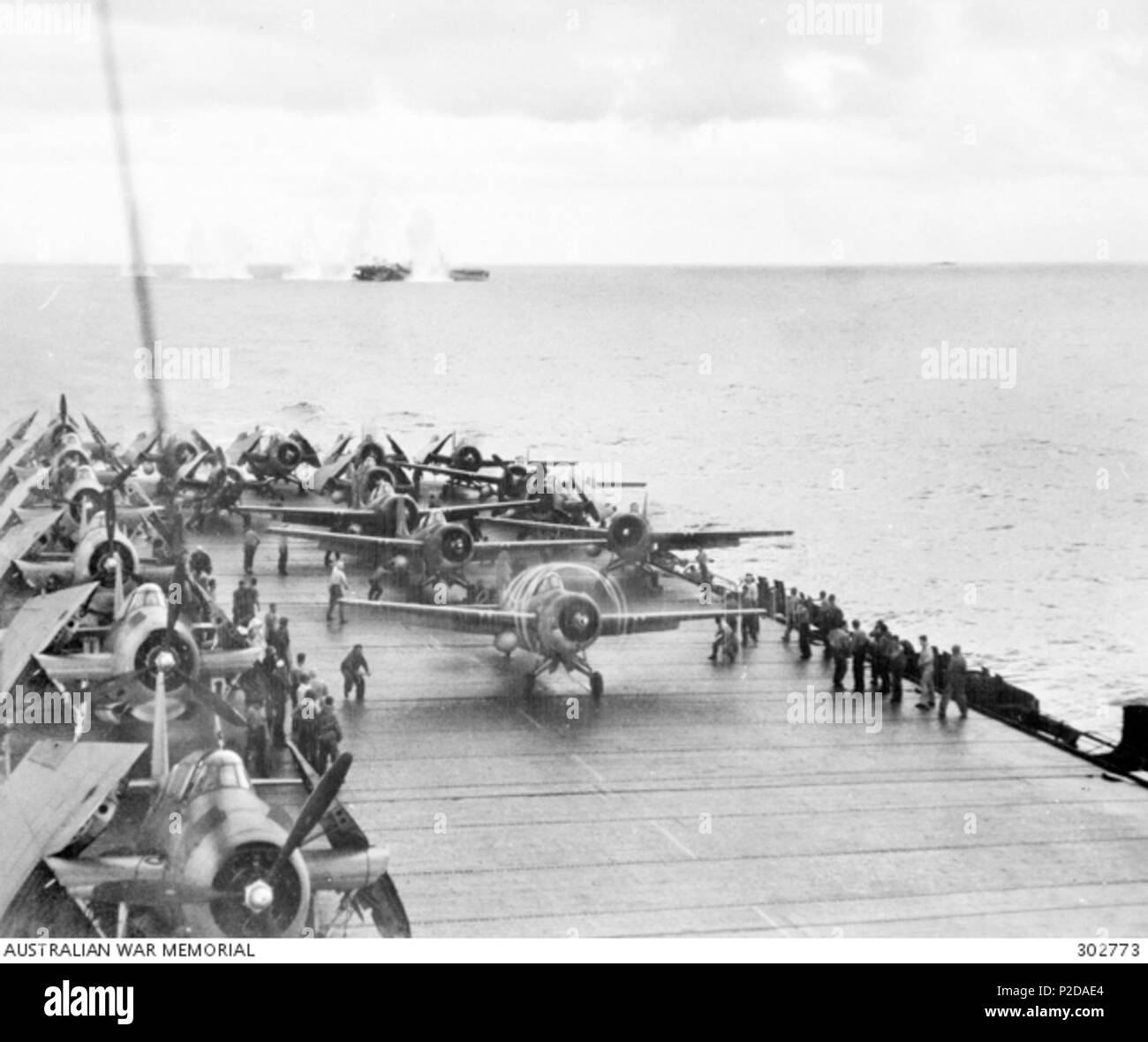 . The U.S. escort carrier USS Kitkun Bay (CVE-71) prepares to launch Grumman FM-2 Wildcat fighters of composite squadron VC-5 during the Battle of Samar on 25 October 1944. The aircraft visible on the left are Grumman TBF Avengers. In the distance, Japanese shells are splashing near the USS White Plains (CVE-66). AWM caption: off Samar, Philippines. 1944-10-25. just after 0700 the sea around the escort aircraft carrier USS White Plains erupts as she is straddled and near missed by 14 inch gunfire from Japanese battleships which have surprised the escort carrier task group 77:4:1. In the foregr Stock Photo
