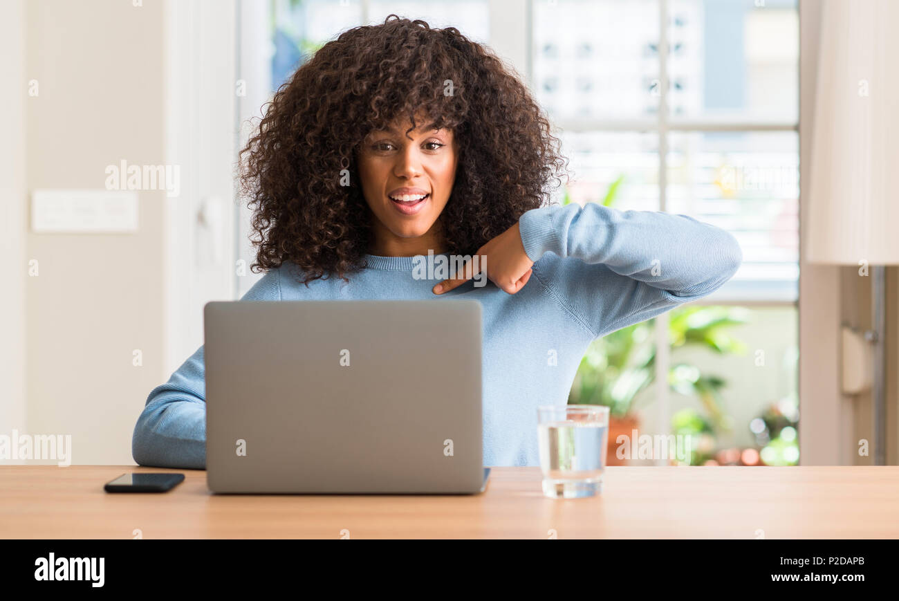 African american woman using laptop computer at home with surprise face ...
