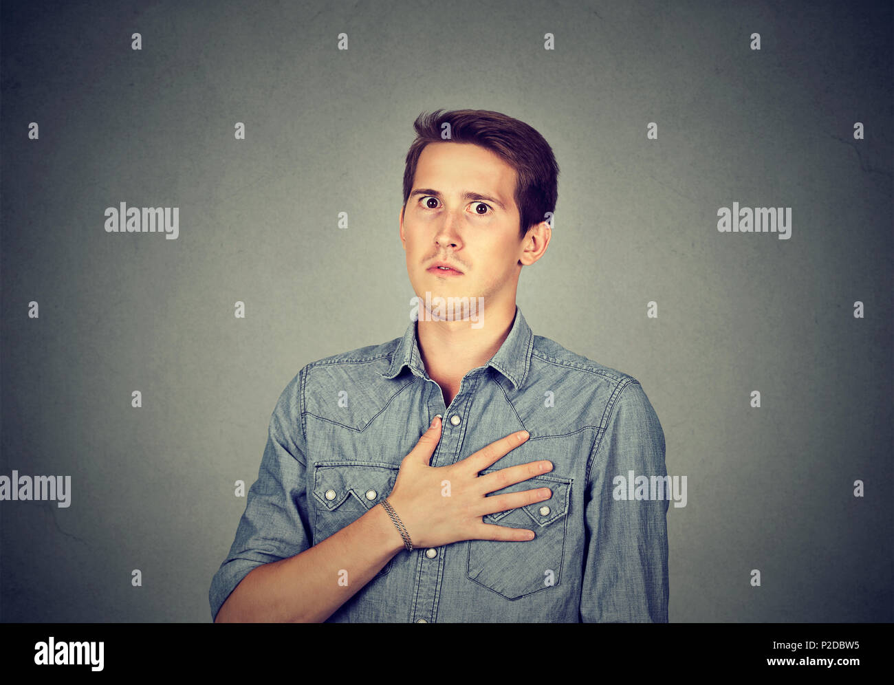 Young man looking super dumbfounded with unbelievable news holding hand on chest and looking stunned at camera Stock Photo