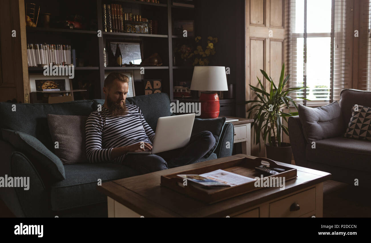 Man sitting on sofa using his laptop Stock Photo