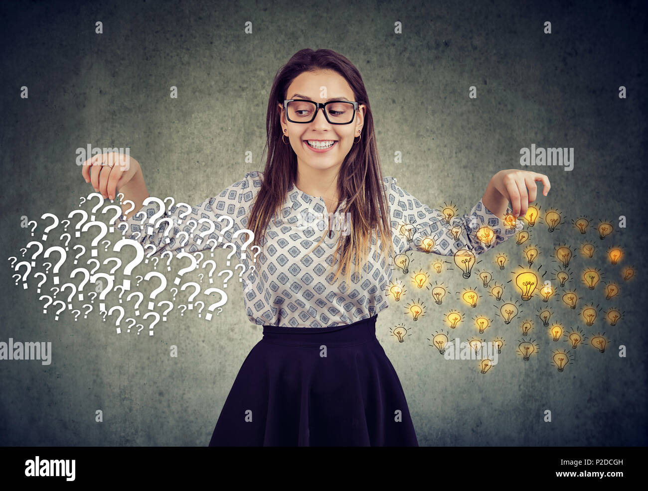 Happy young woman with many questions and answers ideas light bulbs on gray wall background Stock Photo