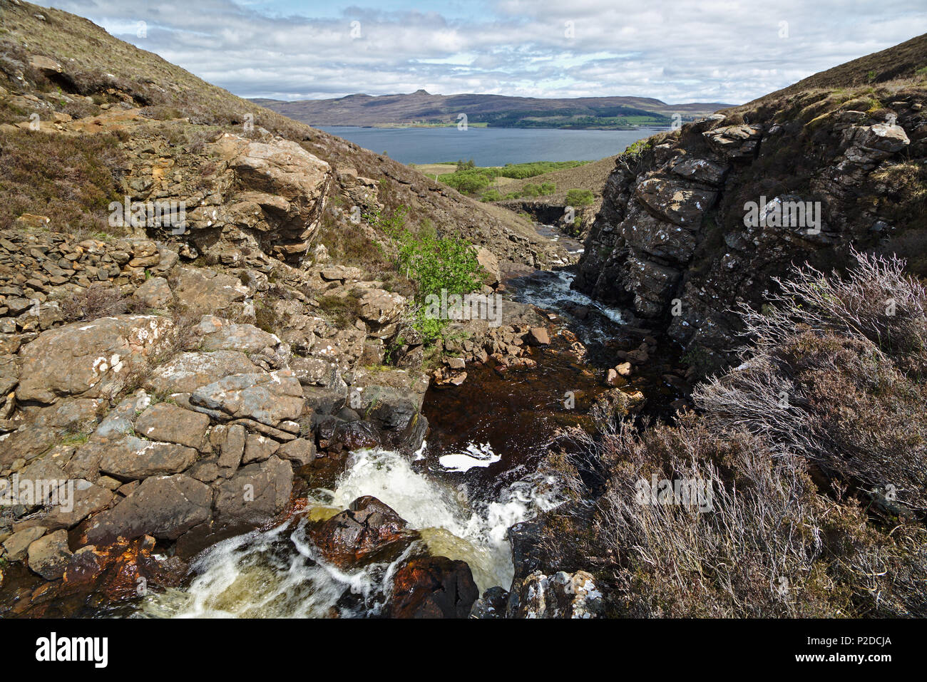 Isle of Skye, Scotland - Downstream view of a waterfall of the river Ollach running through a narrow gorge with the Sound of Raasay in the distance Stock Photo
