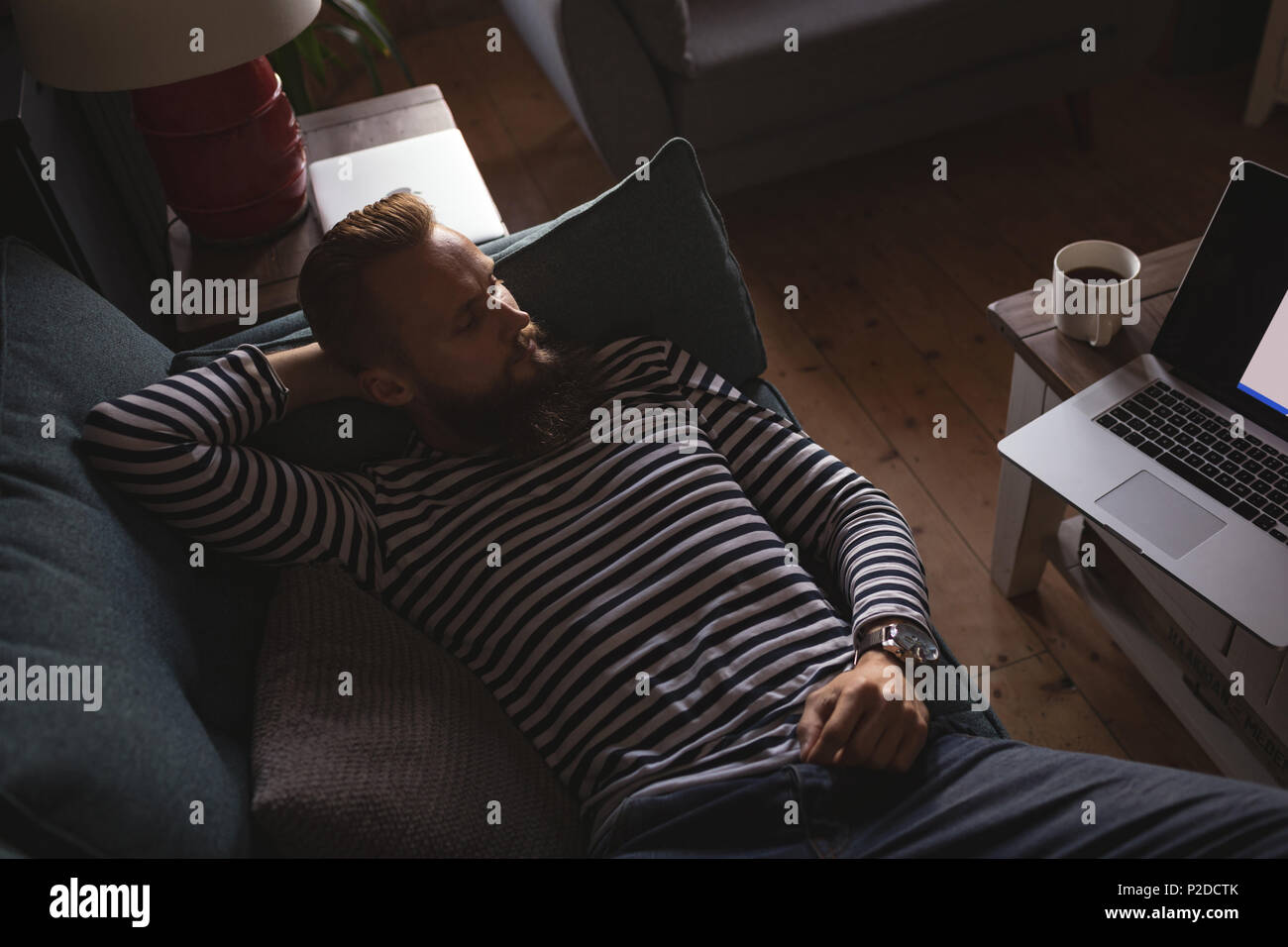 man lying on sofa watching laptop Stock Photo
