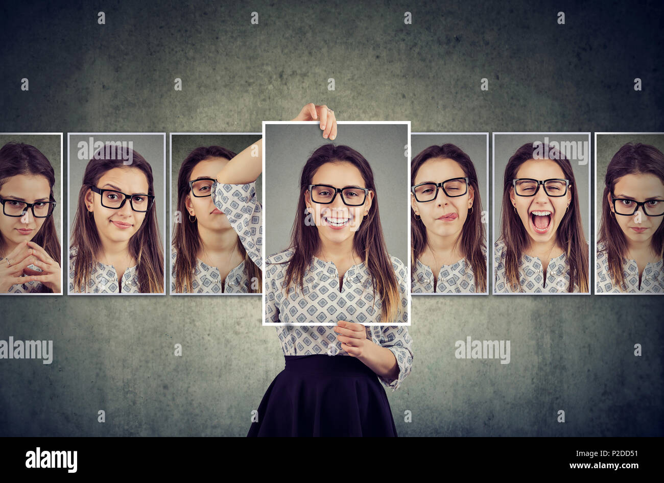 Girl holds and changing her face portraits with different expressions. Woman expressing different emotions Stock Photo