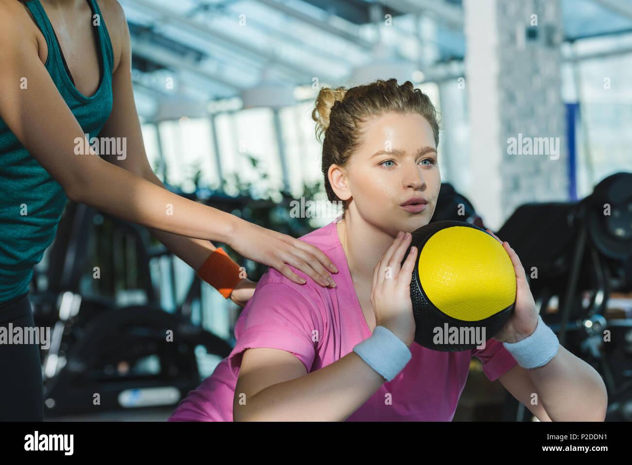 overweight woman training with medicine ball while trainer helping her Stock Photo