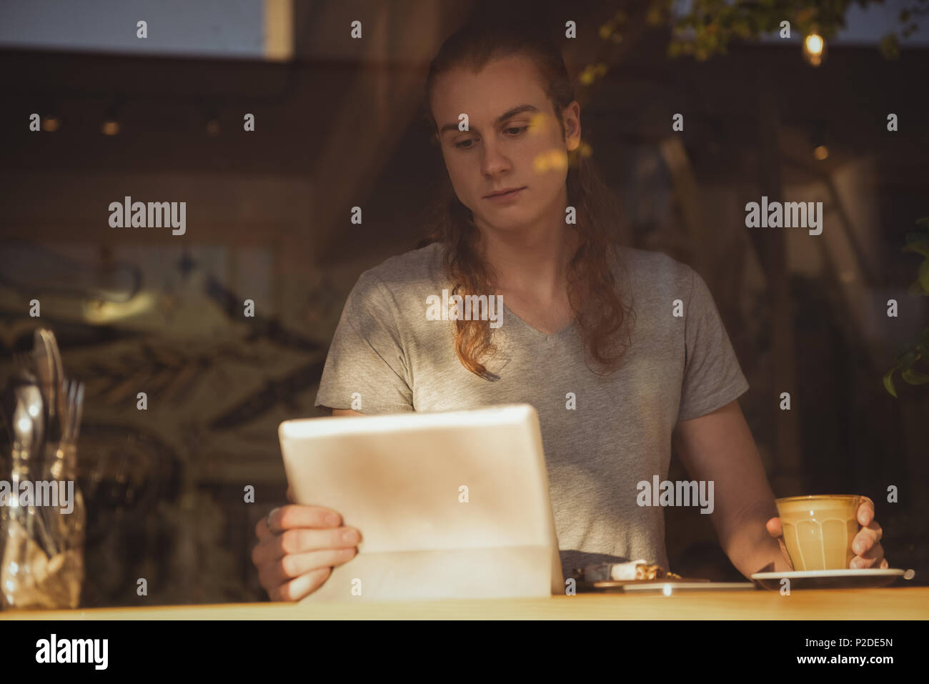 Man using digital tablet while having coffee Stock Photo
