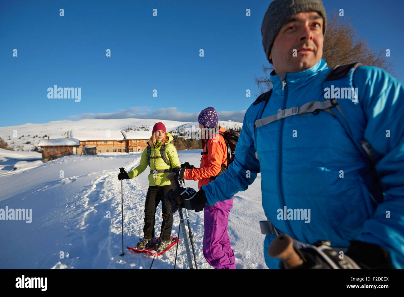 Group of people snow shoeing in front of a mountain hut, Kreuzwiesenalm, Luesen, South Tyrol, Italy Stock Photo