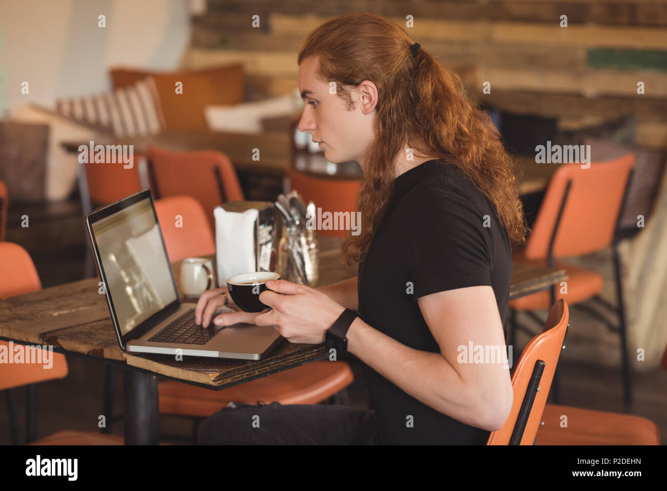 Man using laptop while having coffee Stock Photo