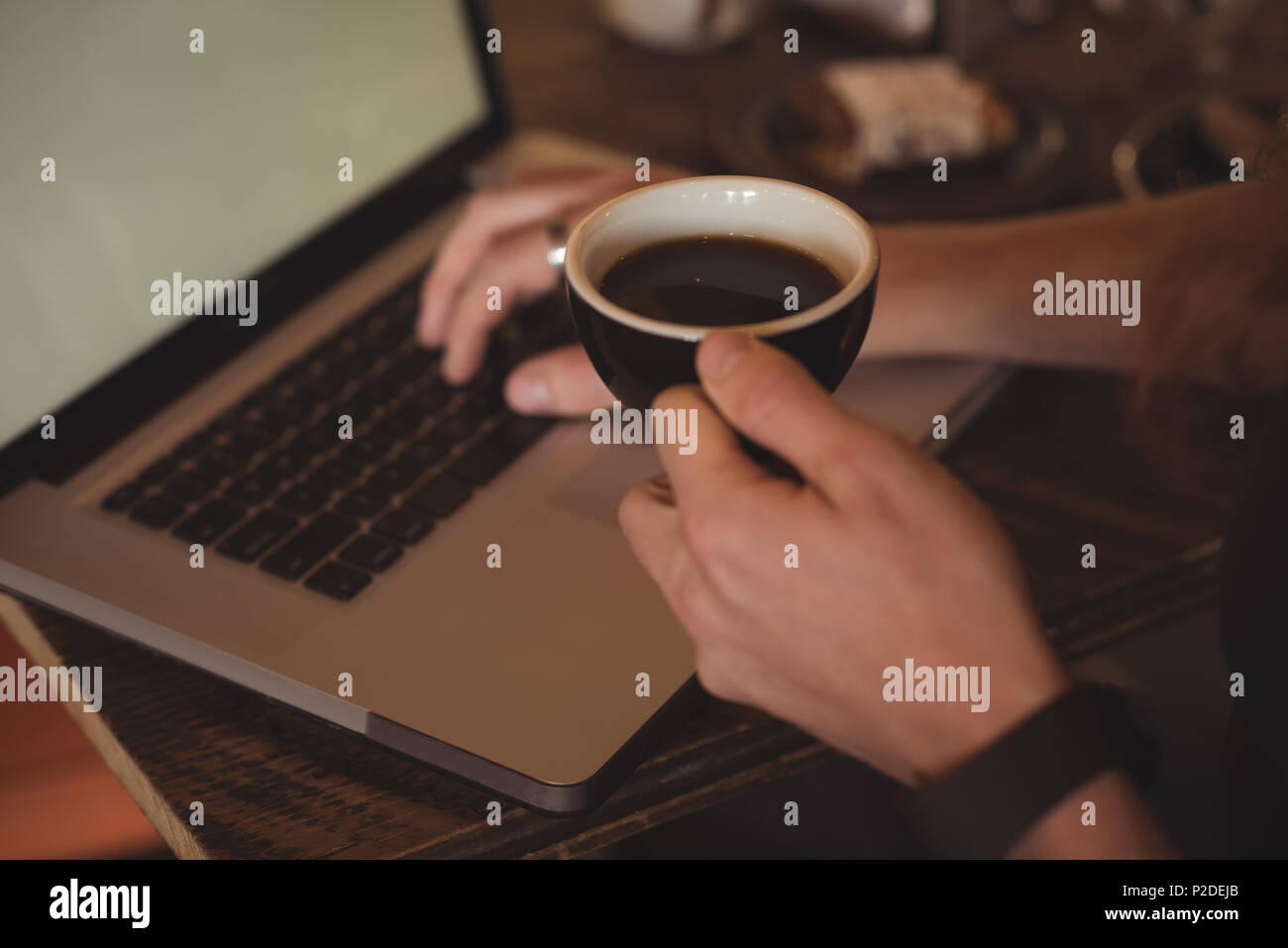 Close-up of man using laptop while having coffee Stock Photo