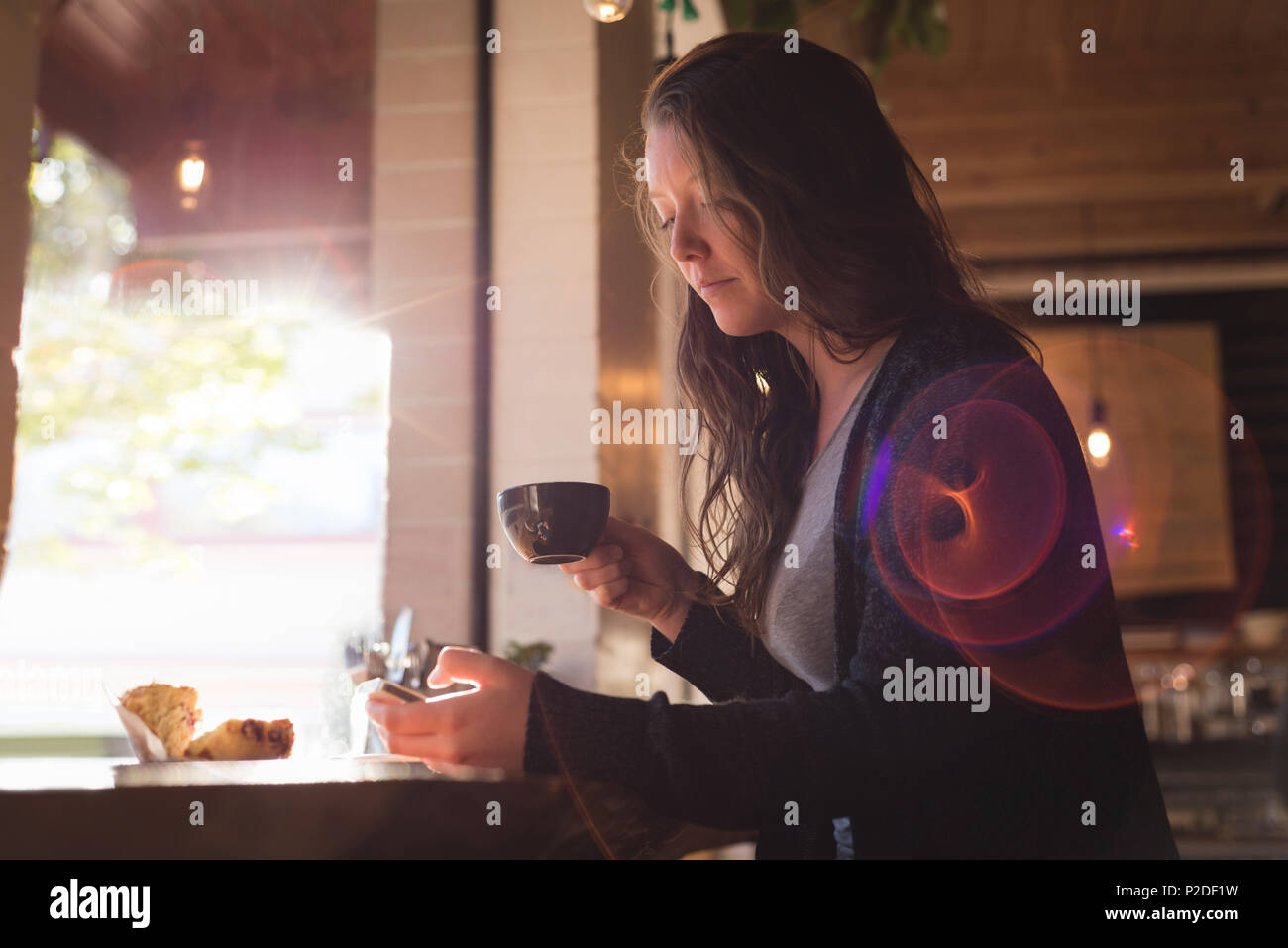 Woman using mobile phone while having coffee Stock Photo