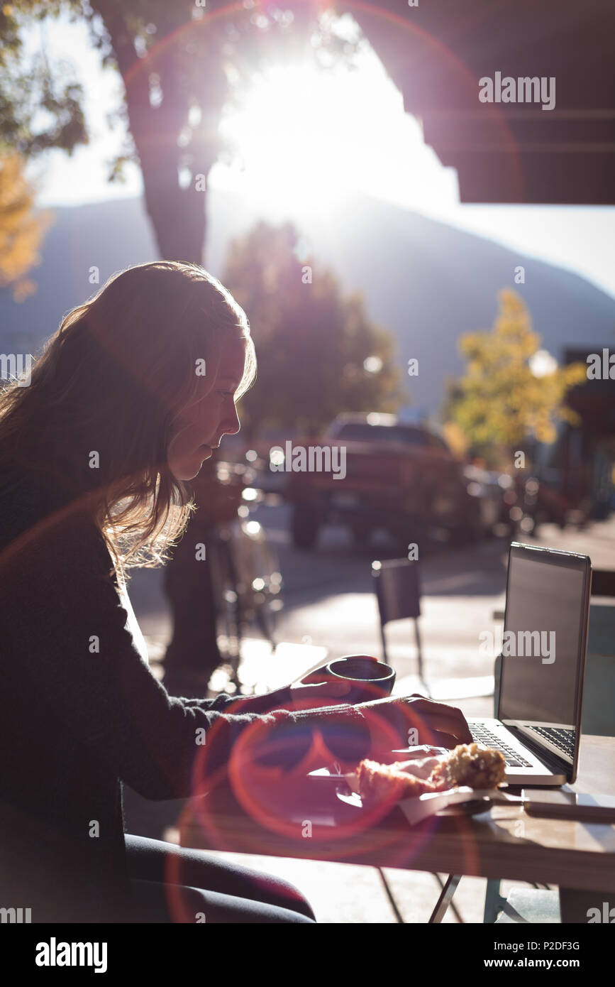 Woman using laptop while having coffee Stock Photo