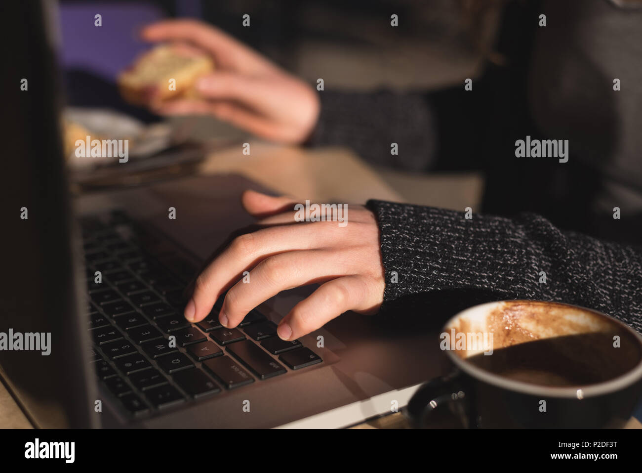 Woman using laptop while having coffee Stock Photo