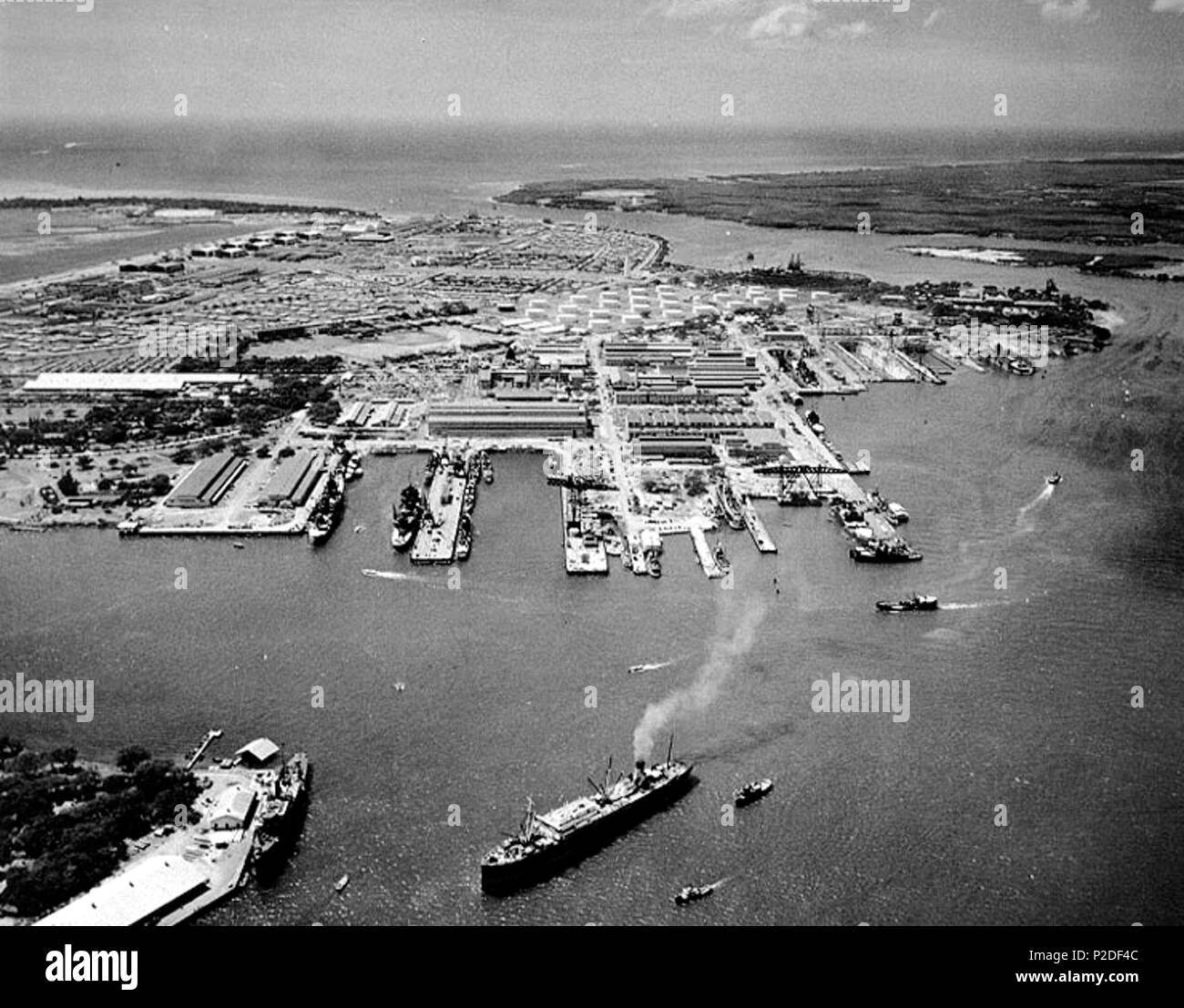. Aerial photograph of the U.S. Navy Pearl Harbor Navy Yard, Oahu, Hawaii (USA), looking toward the southwest, taken on 13 October 1941, with the fuel tank farm in the center middle distance, the Marine Barracks to the left with Hickam Army Air Base beyond, and the harbour entrance channel in the center background. The passenger steamer Maui is in the lower center, with USS Oglala (CM-4) at the pier just to the left. A fuel oil barge (YO) is passing the end of 1010 Dock, to the right of center. 13 October 1941. USN 40 Pearl Harbor Navy Yard in October 1941 Stock Photo