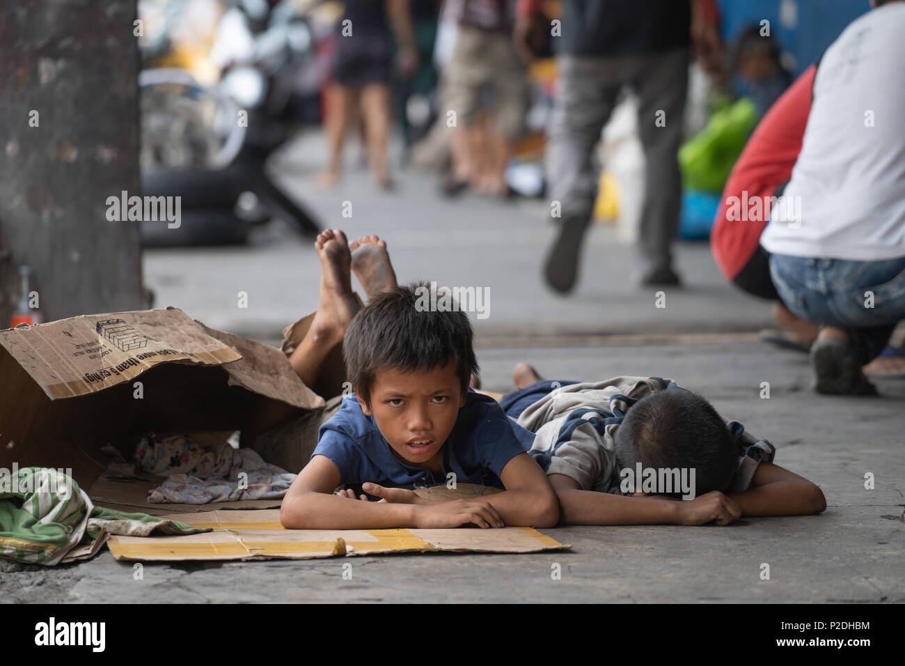 Street children in Cebu City,Philippines on the sidewalk lying on cardboard which they use as bedding when sleeping. Stock Photo