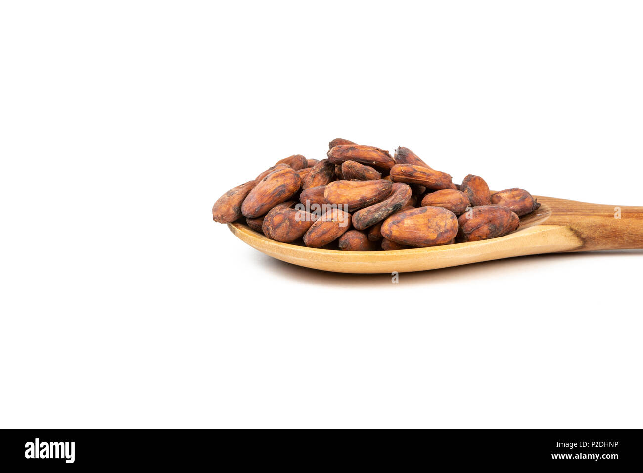 Close up of cocoa beans in wooden spoon on white background. Stock Photo