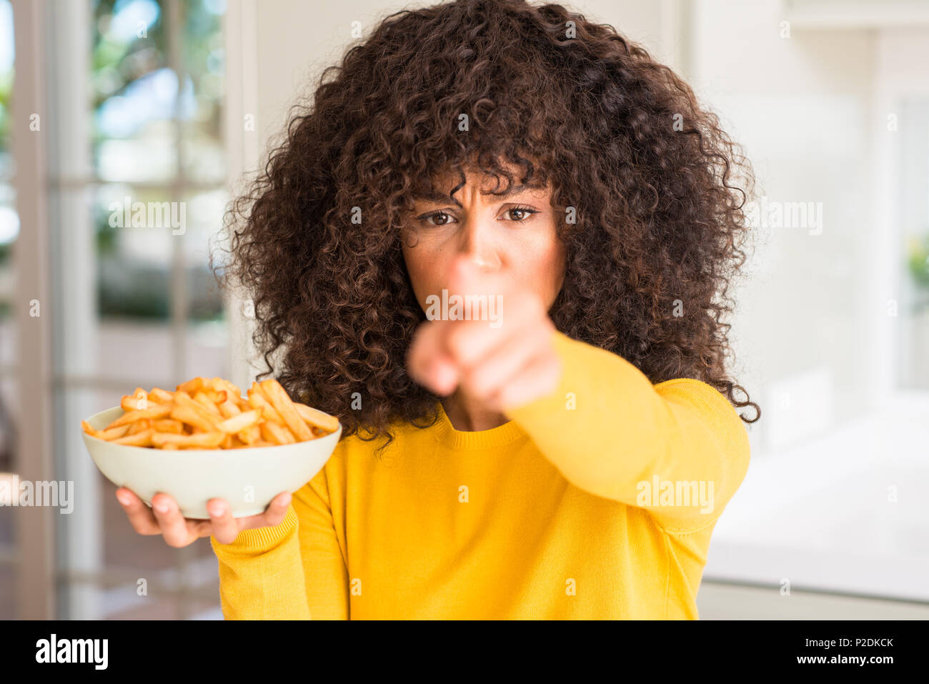 African american woman holding a plate with potato chips at home ...