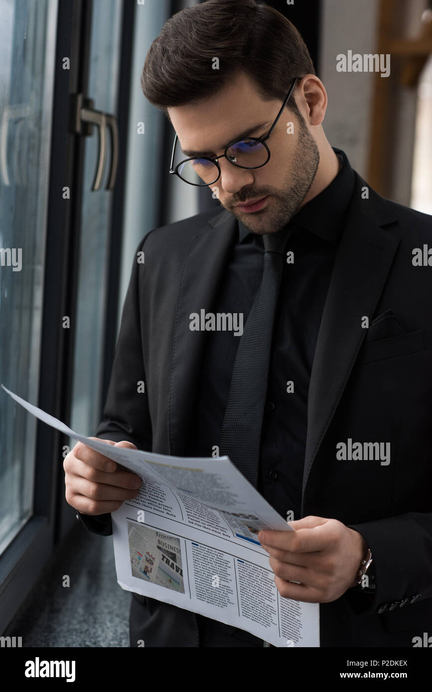 Young businessman in glasses reading newspaper Stock Photo - Alamy