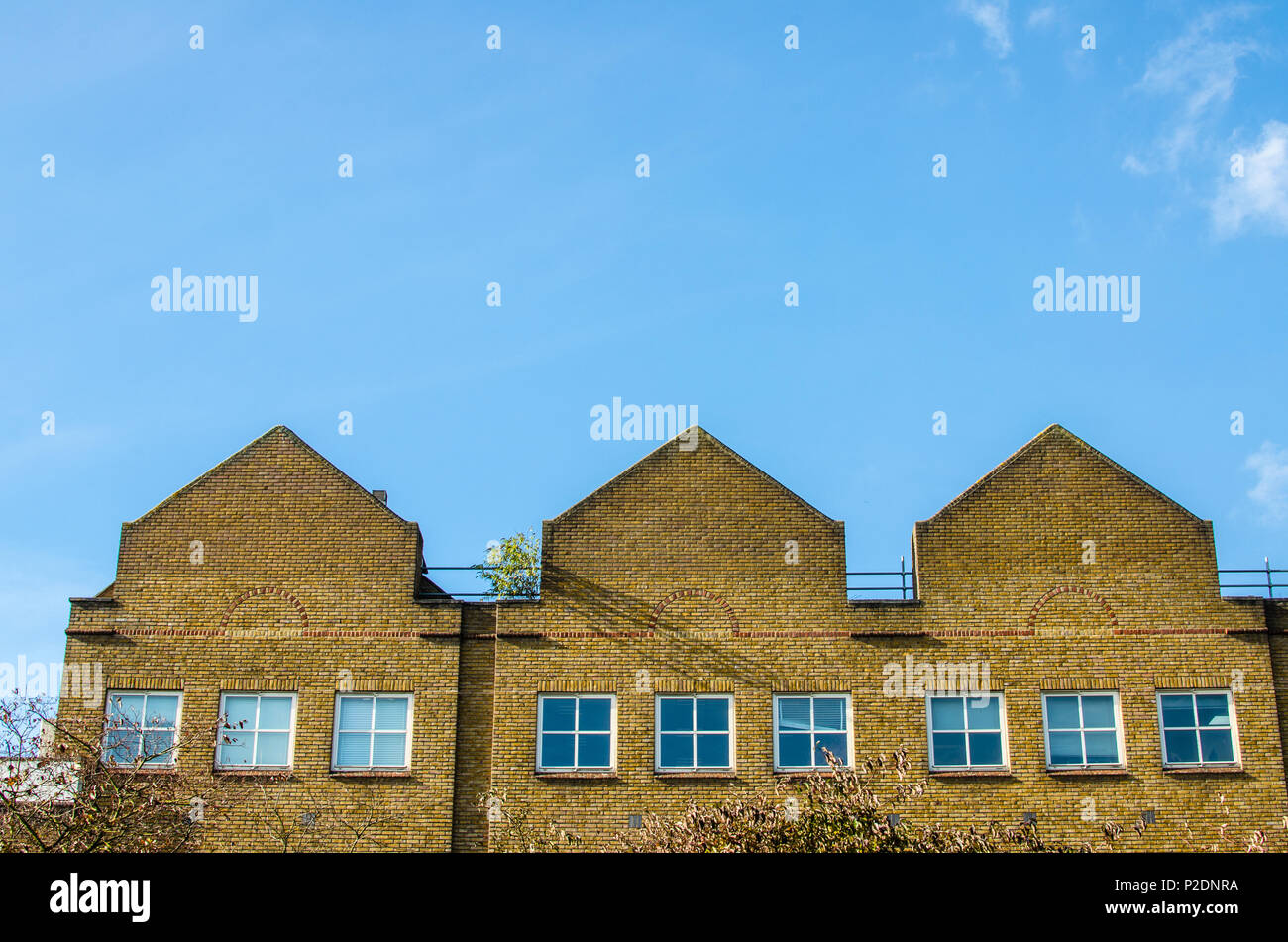 Converted red brick industrial building against a blue sky in London Stock Photo
