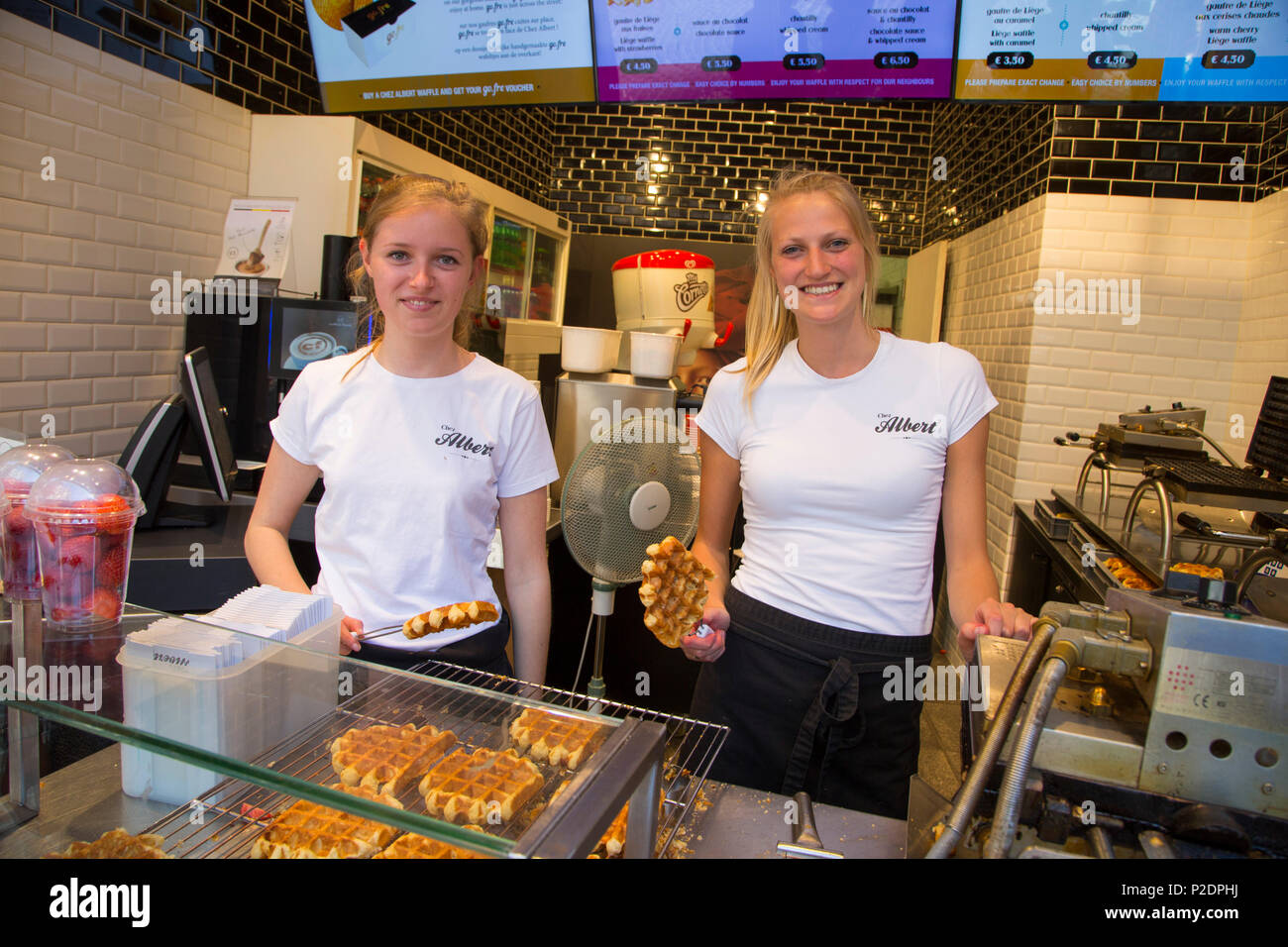 Two young women selling delicious Belgian waffles at Chez Albert bakery and waffle shop in the Old Town, Bruges Brugge, Flemish Stock Photo