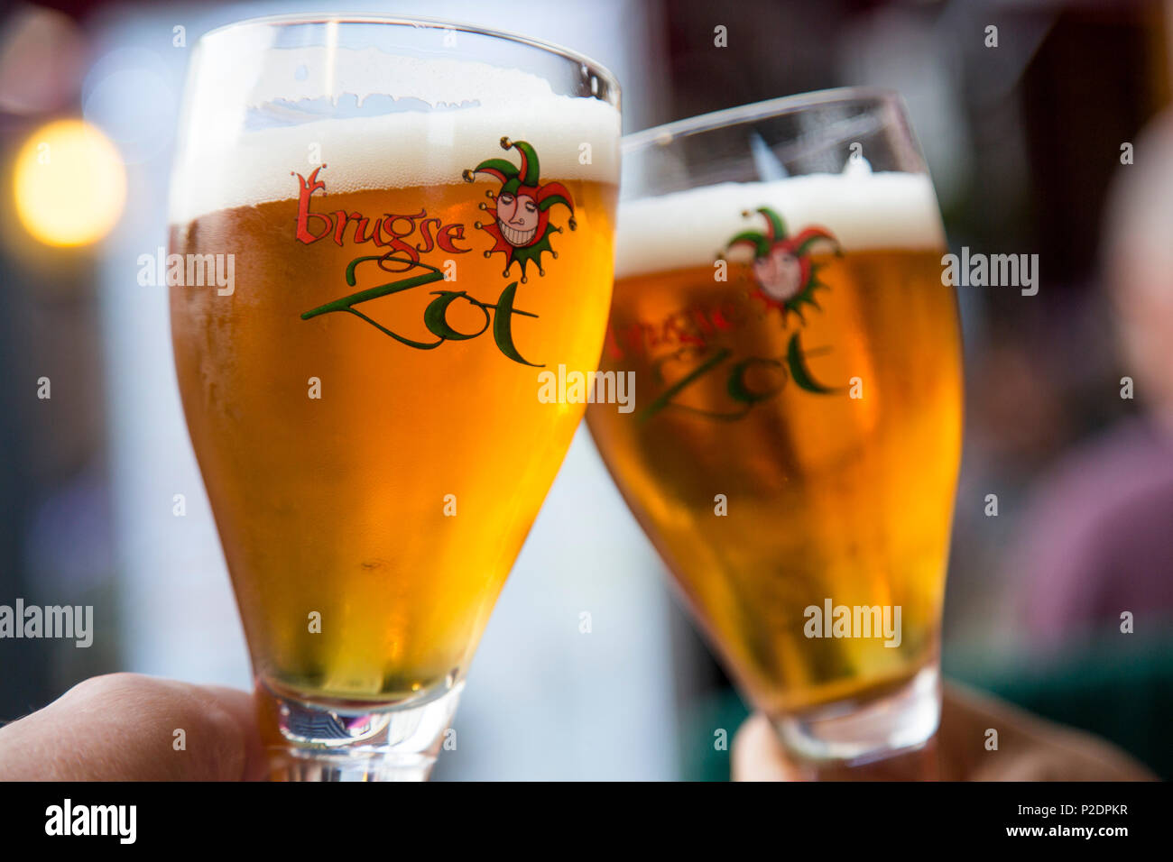 Toasting with two glasses of Brugse Zot beer in a restaurant in the Old Town, Bruges Brugge, Flemish Region, Belgium Stock Photo