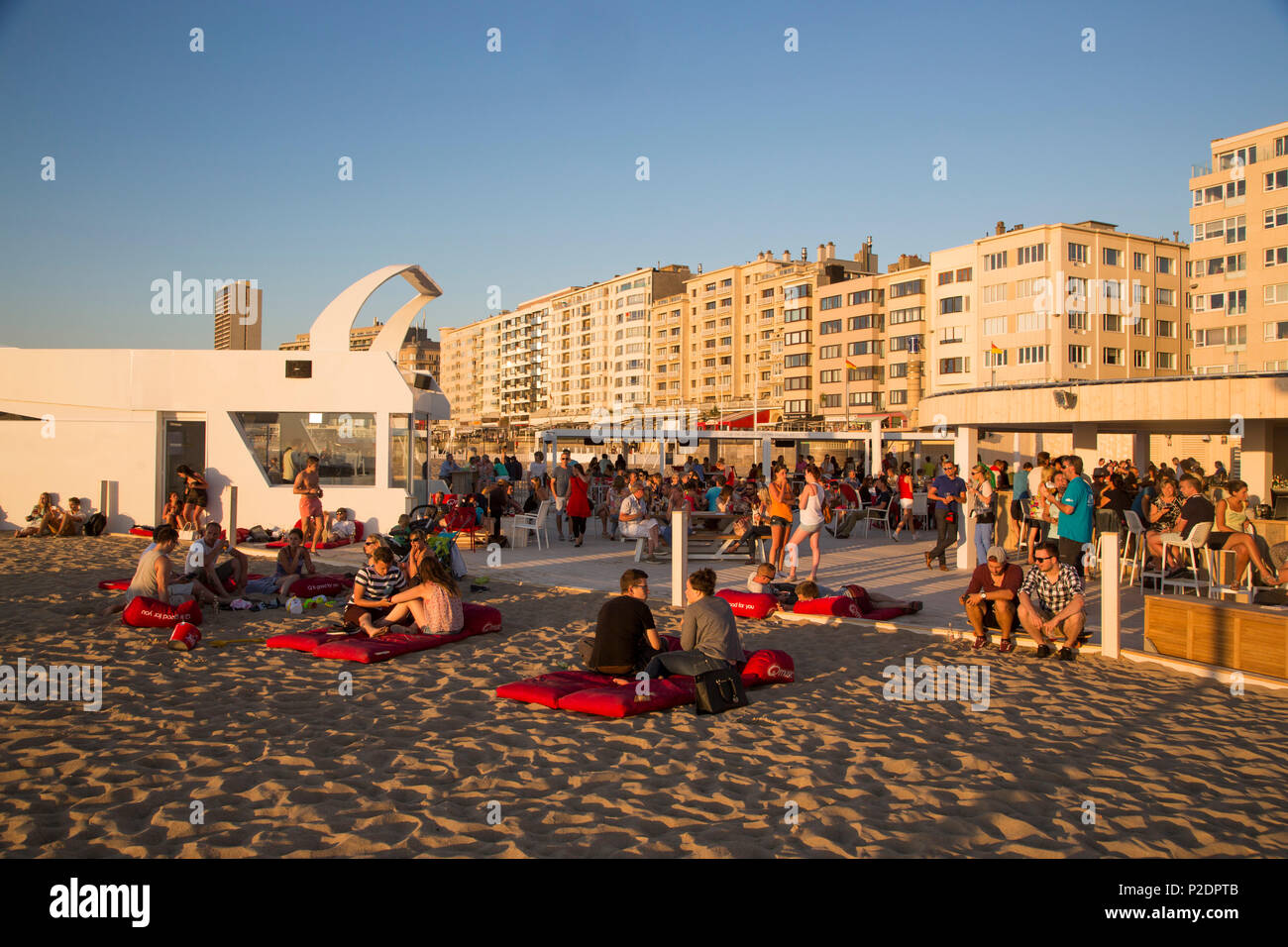 People chilling on the beach at a beach lounge with apartment buildings behind, Ostend, Flanders, Flemish Region, Belgium Stock Photo