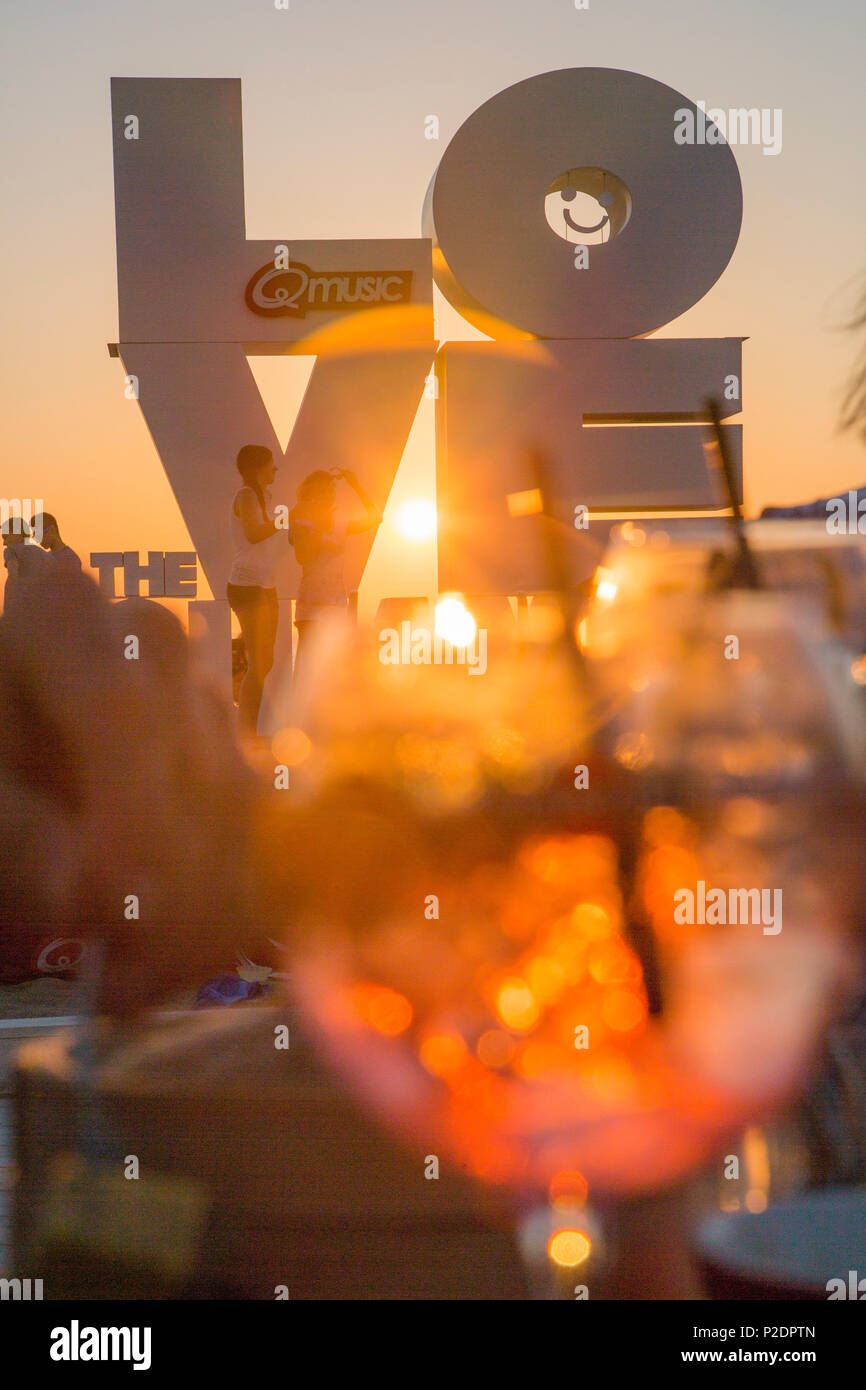 Love sculpture on the beach seen through a cocktail glass at sunset, Ostend, Flanders, Flemish Region, Belgium Stock Photo