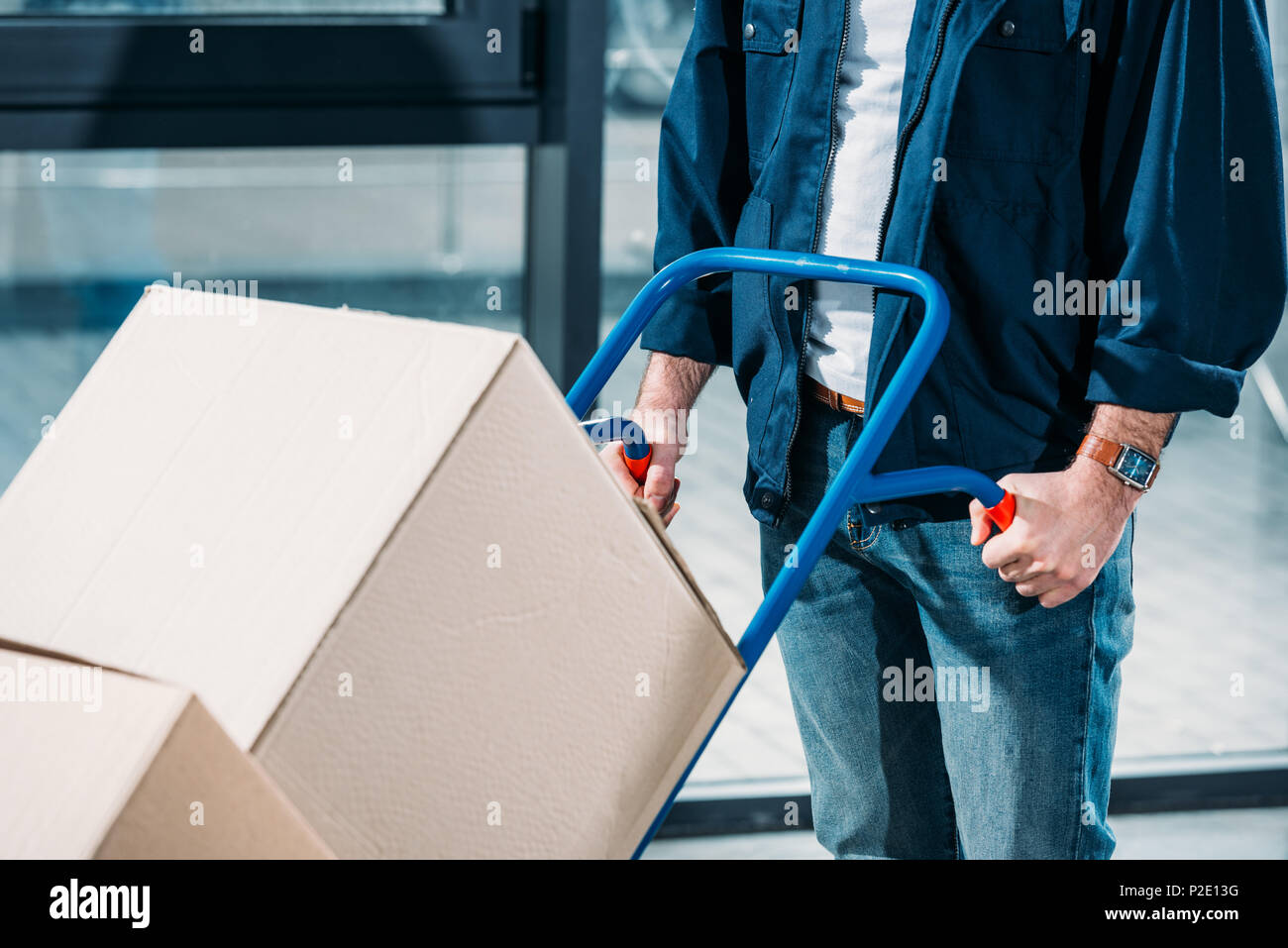 Close-up view of man pushing hand truck with boxes Stock Photo