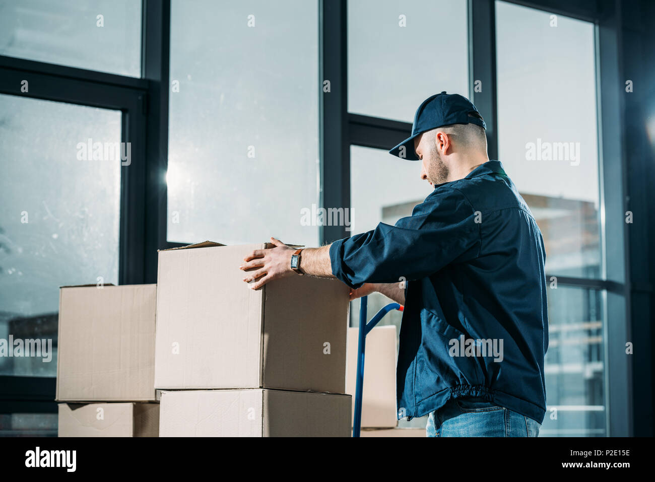 Courier stacking cardboard boxes on handcart Stock Photo